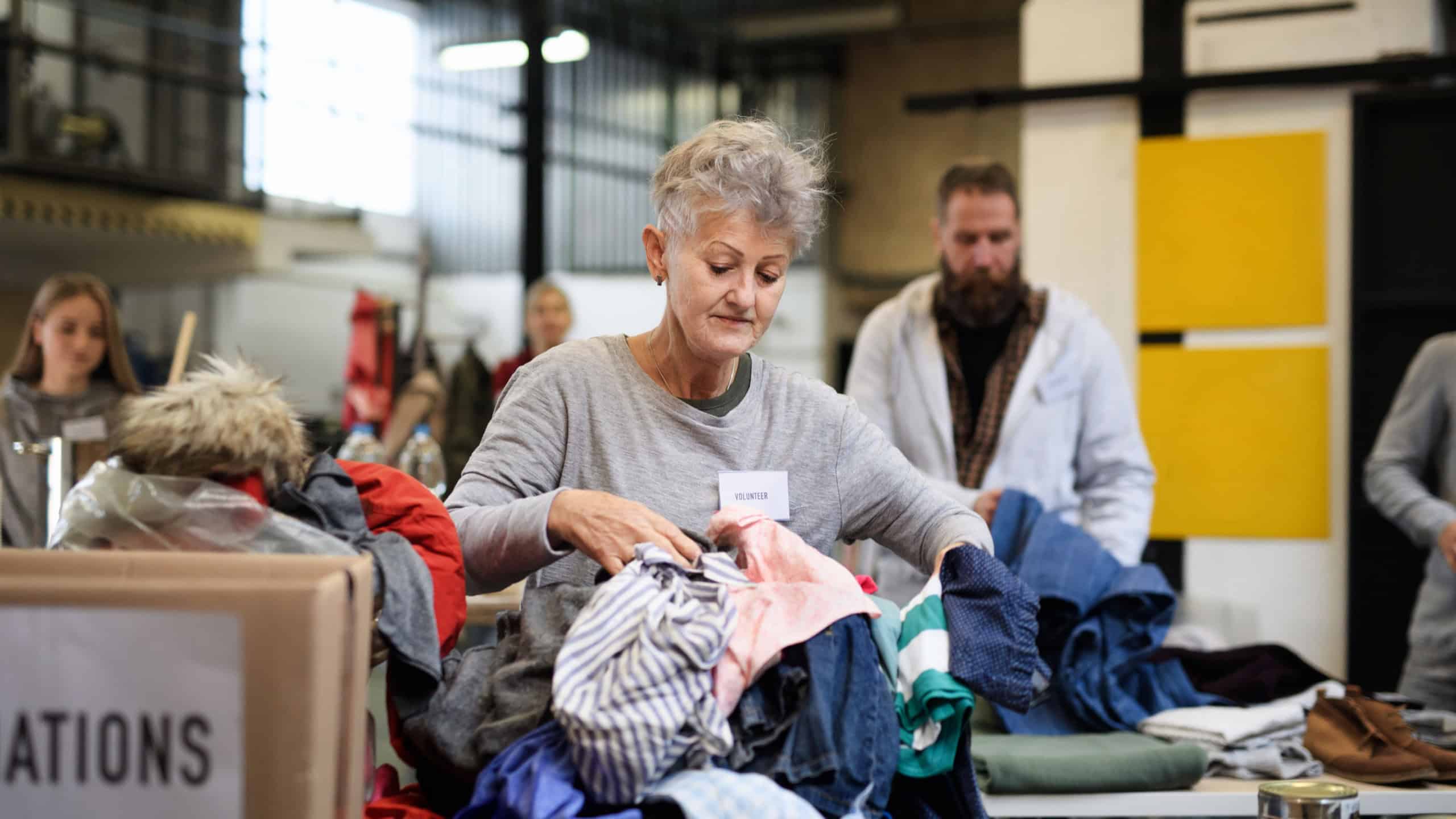 Volunteers sorting out donated clothes in community charity donation center.