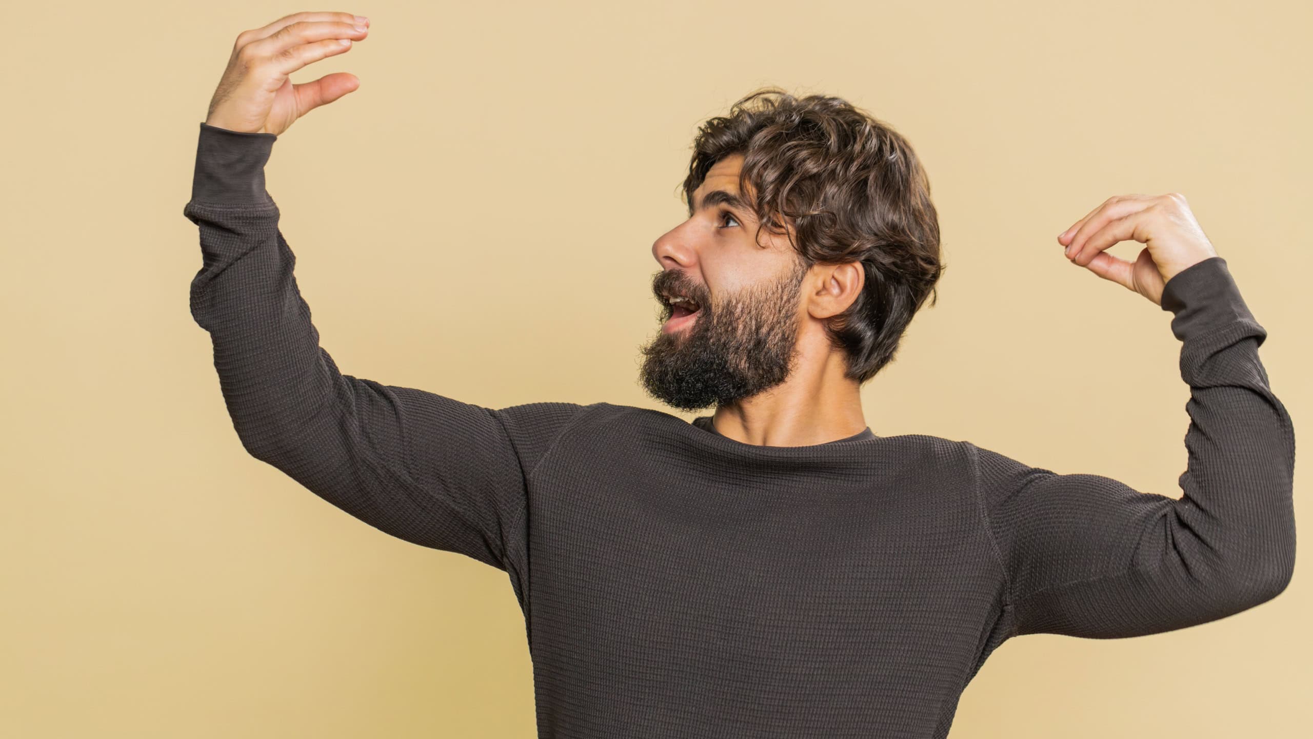 Indian young man showing bla-bla-bla nonsense gesture with hands and rolling eyes, gossips, empty promises, blah concept. Liars. Lebanese Hindu guy isolated alone on beige studio wall background.