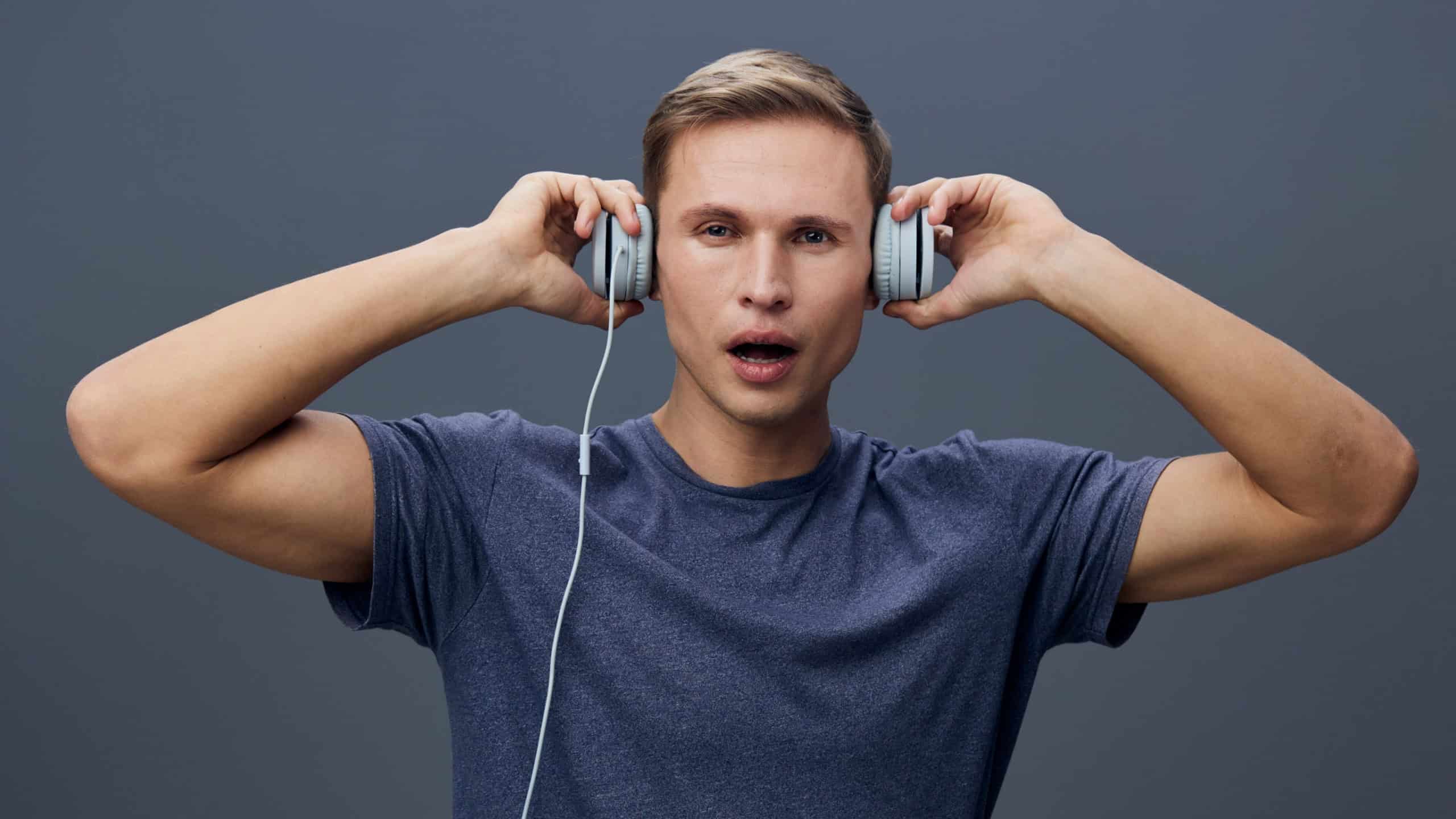 Man wearing casual t-shirt with headphones listening to music, expressing surprise or amazement, isolated on plain gray background, studio portrait, lifestyle concept, digital illustration, vibrant