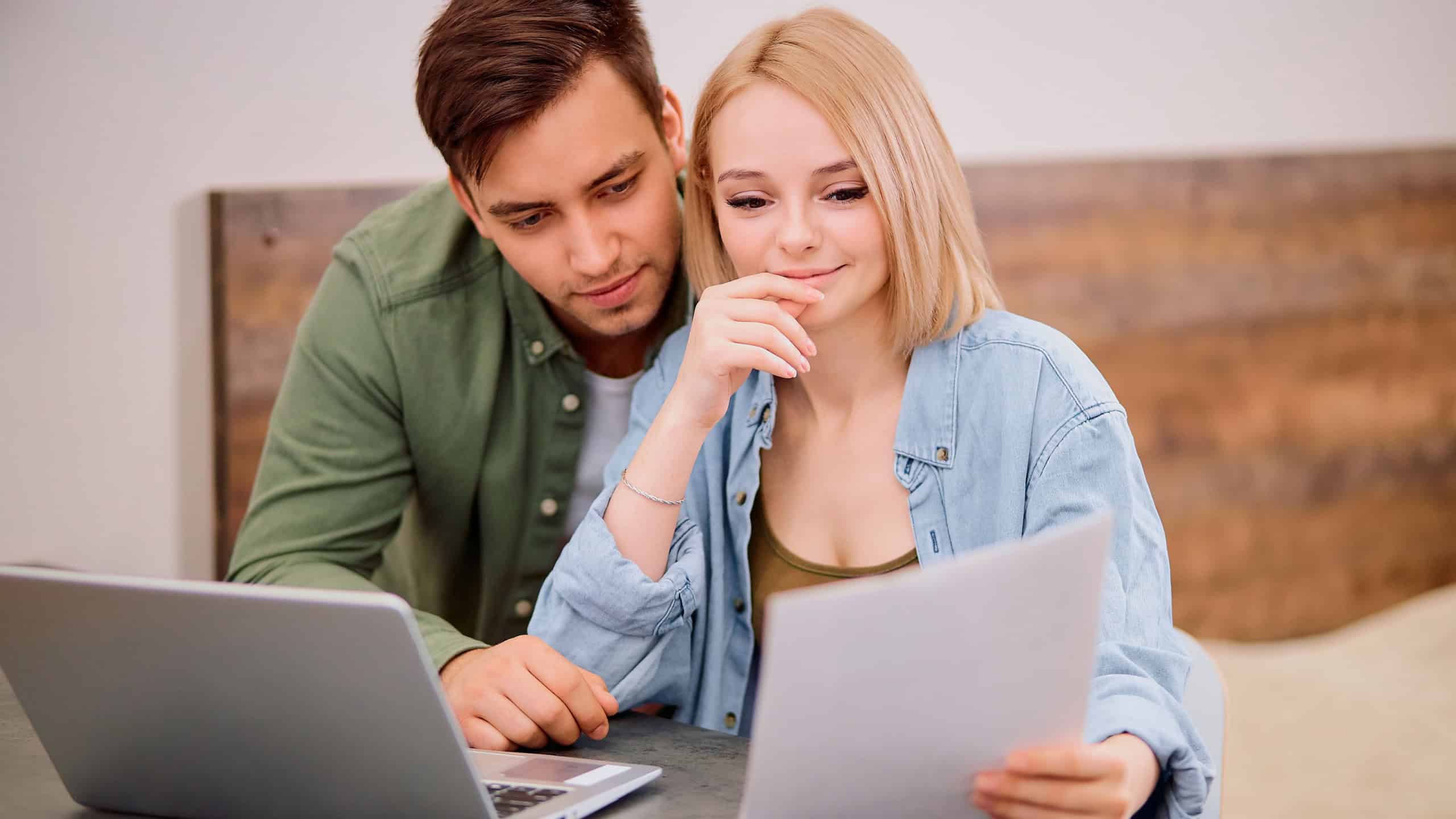 married couple thinking about future together at home, using laptop and checking documents, dream about new house
