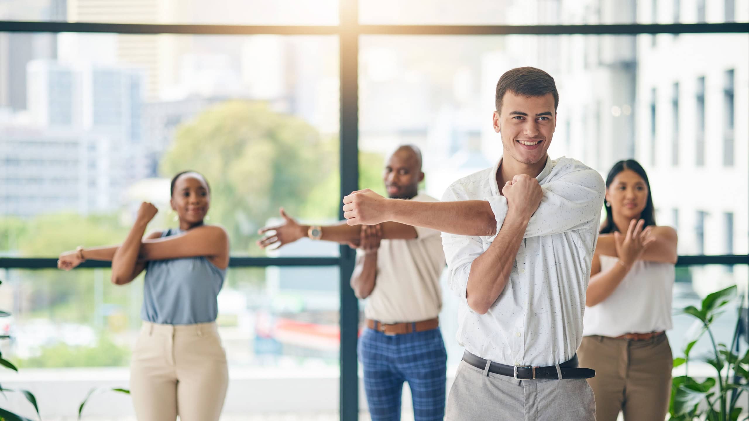 Workout, stretching and a group of business people in the office to exercise for health or mobility together. Fitness, wellness and coach training an employee team in the workplace for a warm up