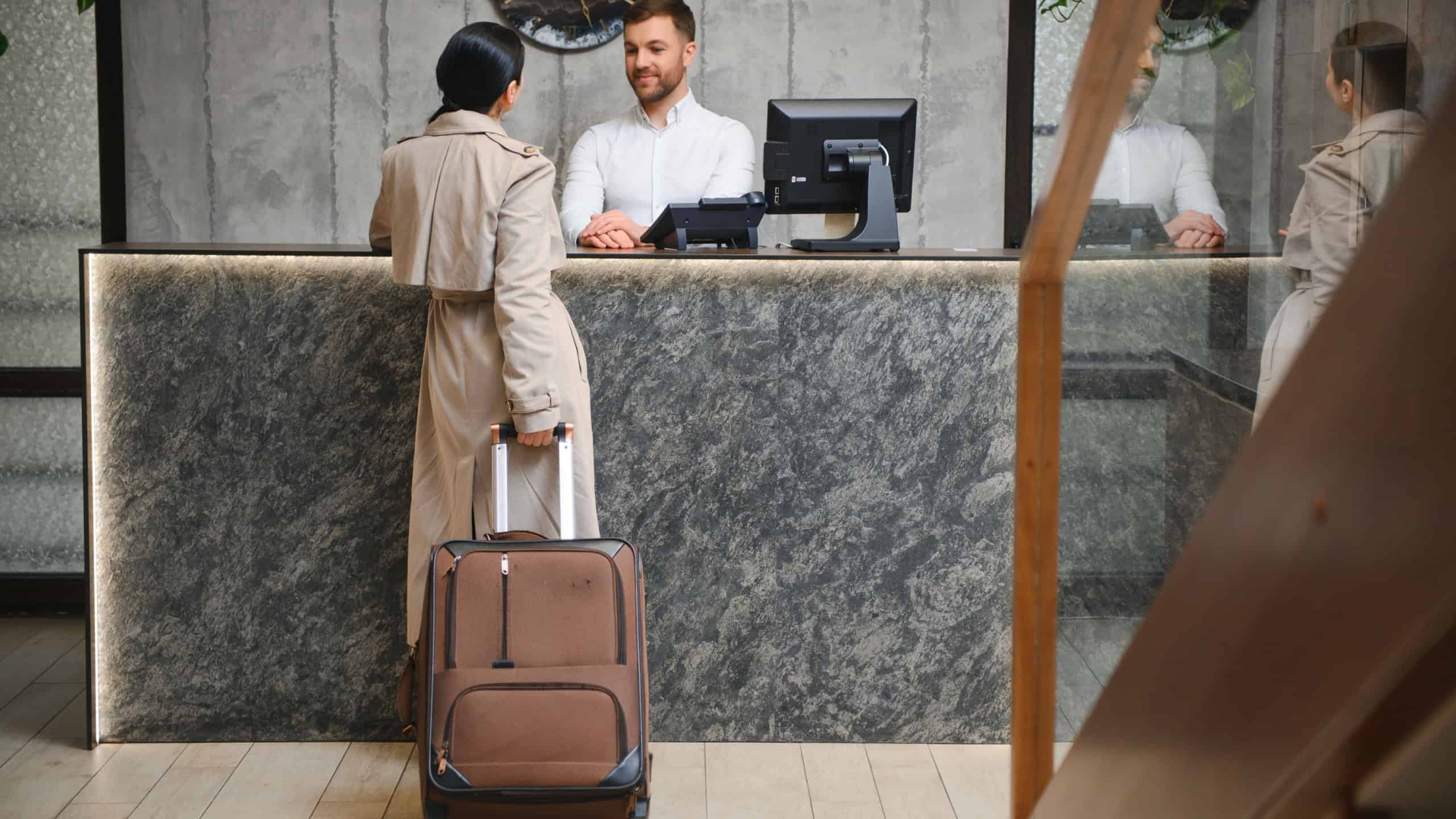 Elegant Business Woman with Travel Trolley Luggage in Hotel Lobby.
