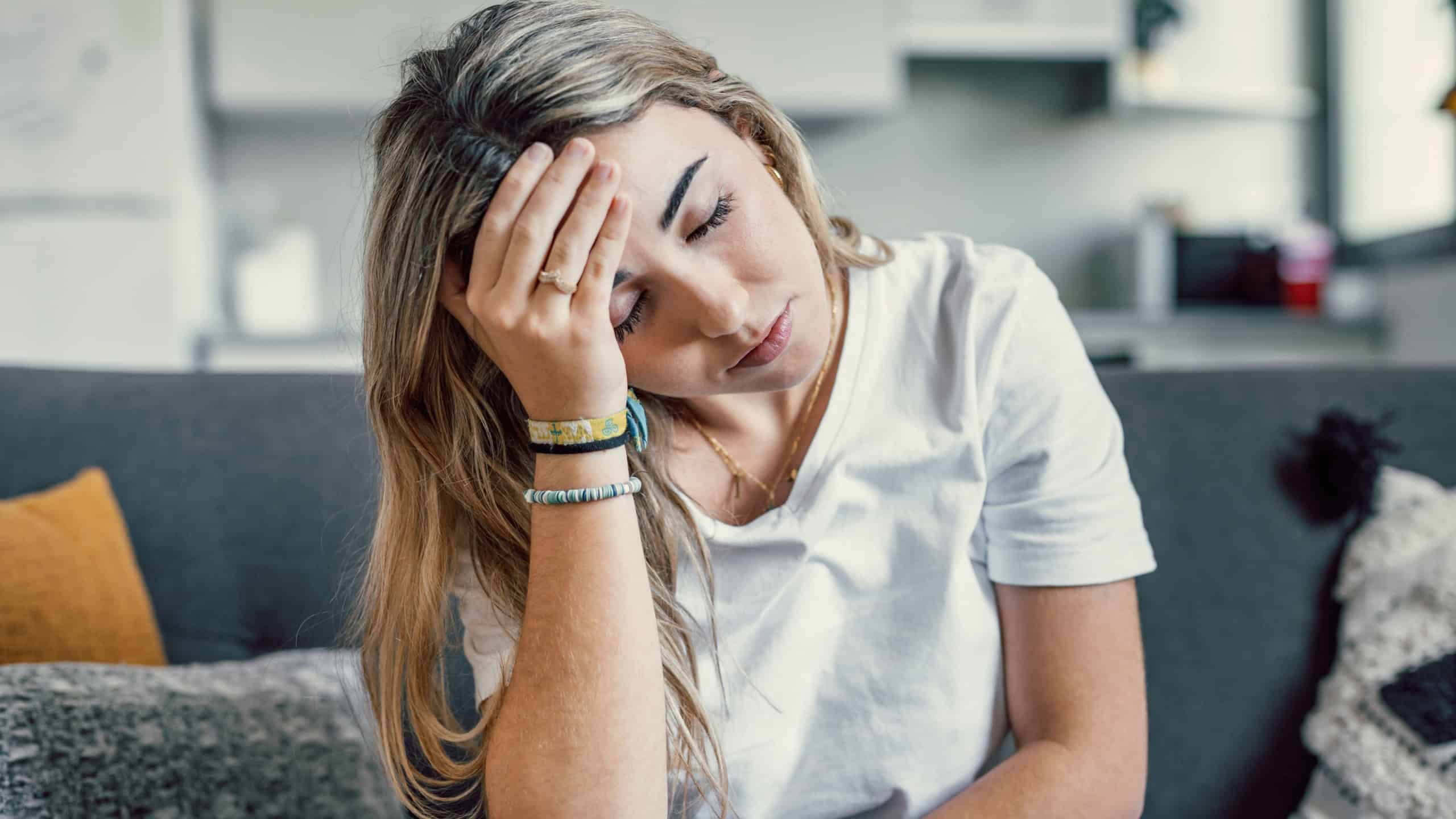 Depressed or tired teen girl feeling stress headache hurt pain sitting alone at home, upset sad heartbroken young woman regret pregnancy or abortion, troubled with problem or psychological trauma