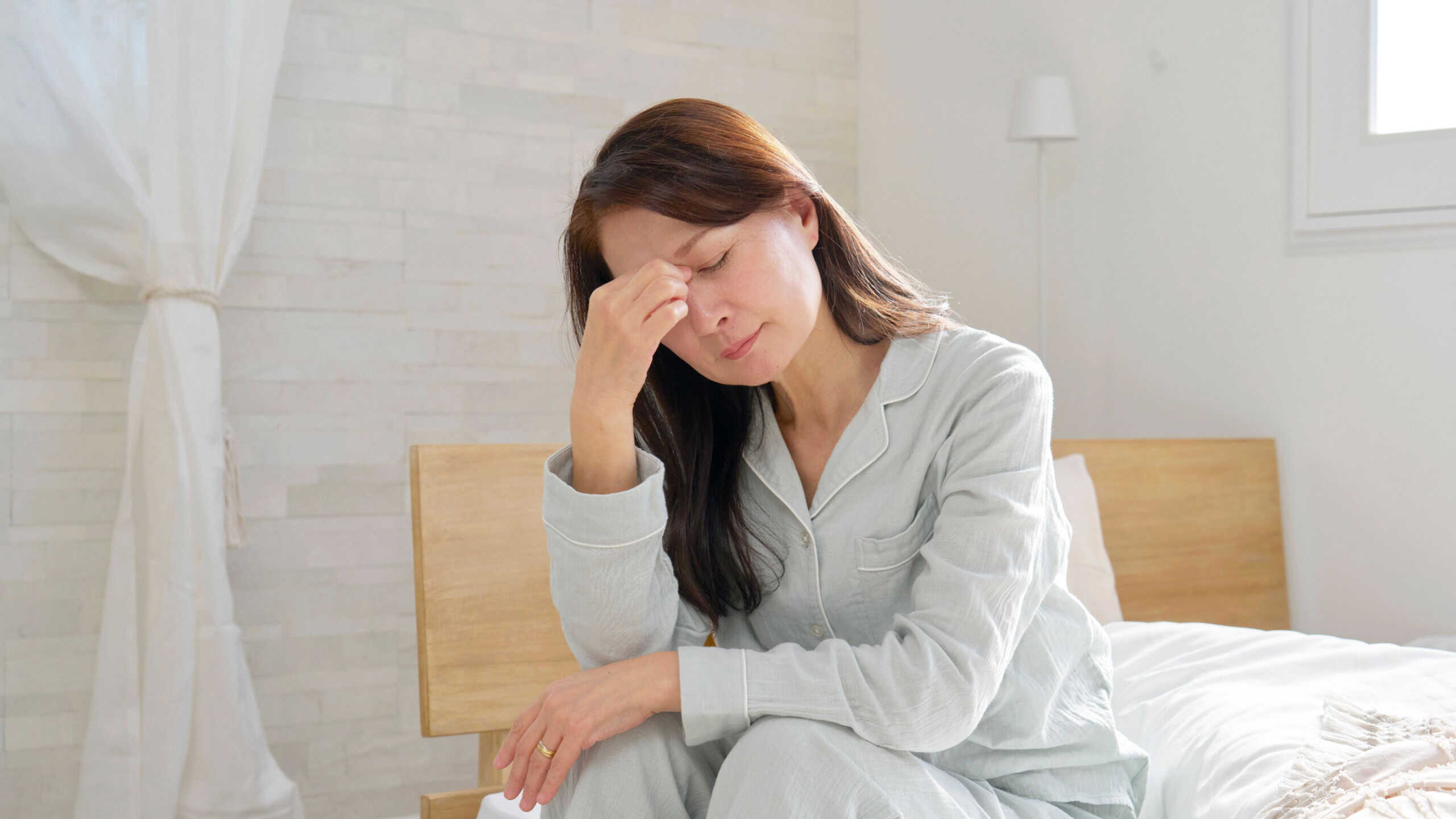 sleepy Asian 60s woman in the pajamas in the room