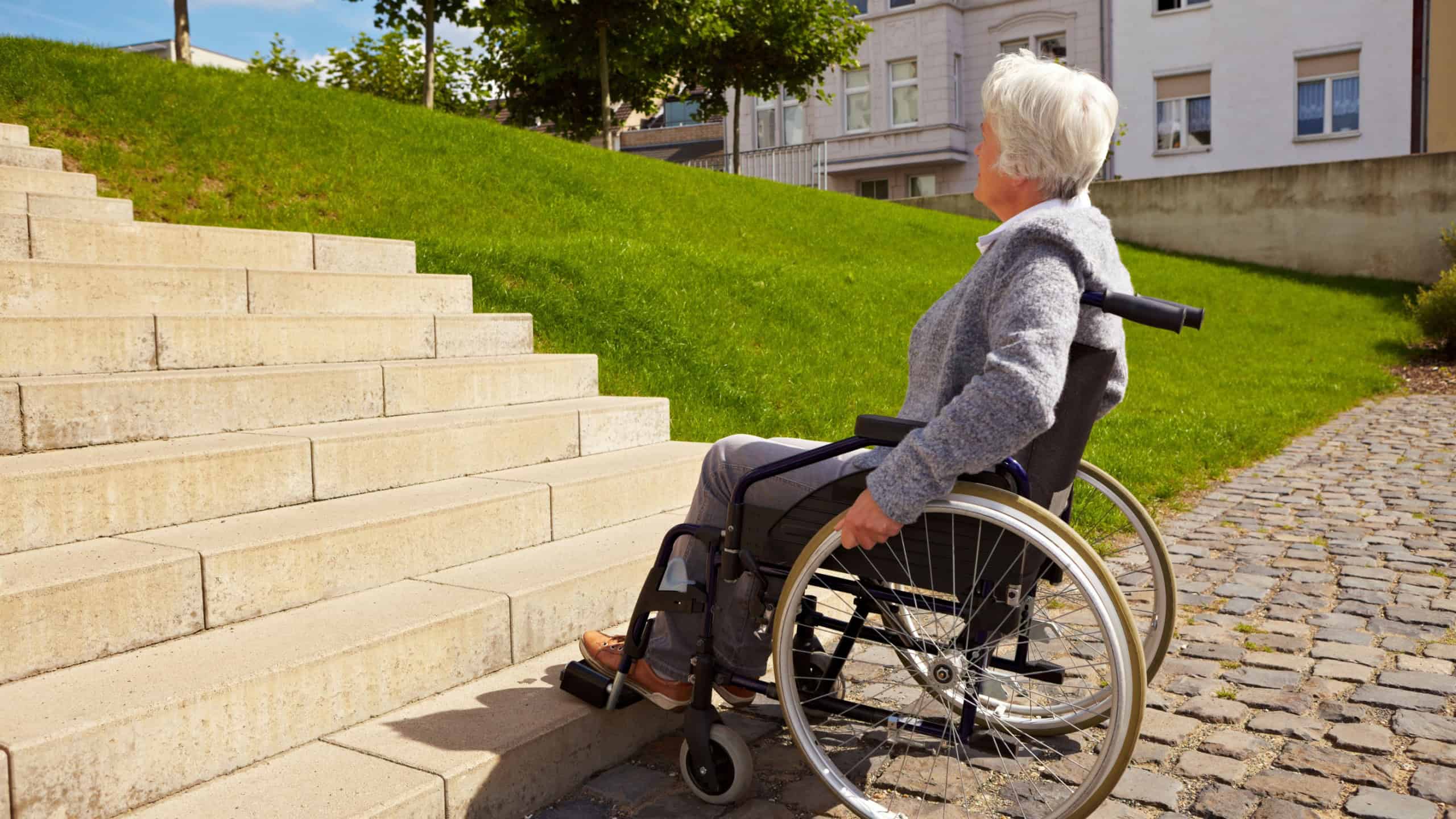 Elderly woman in wheelchair looking at stairs