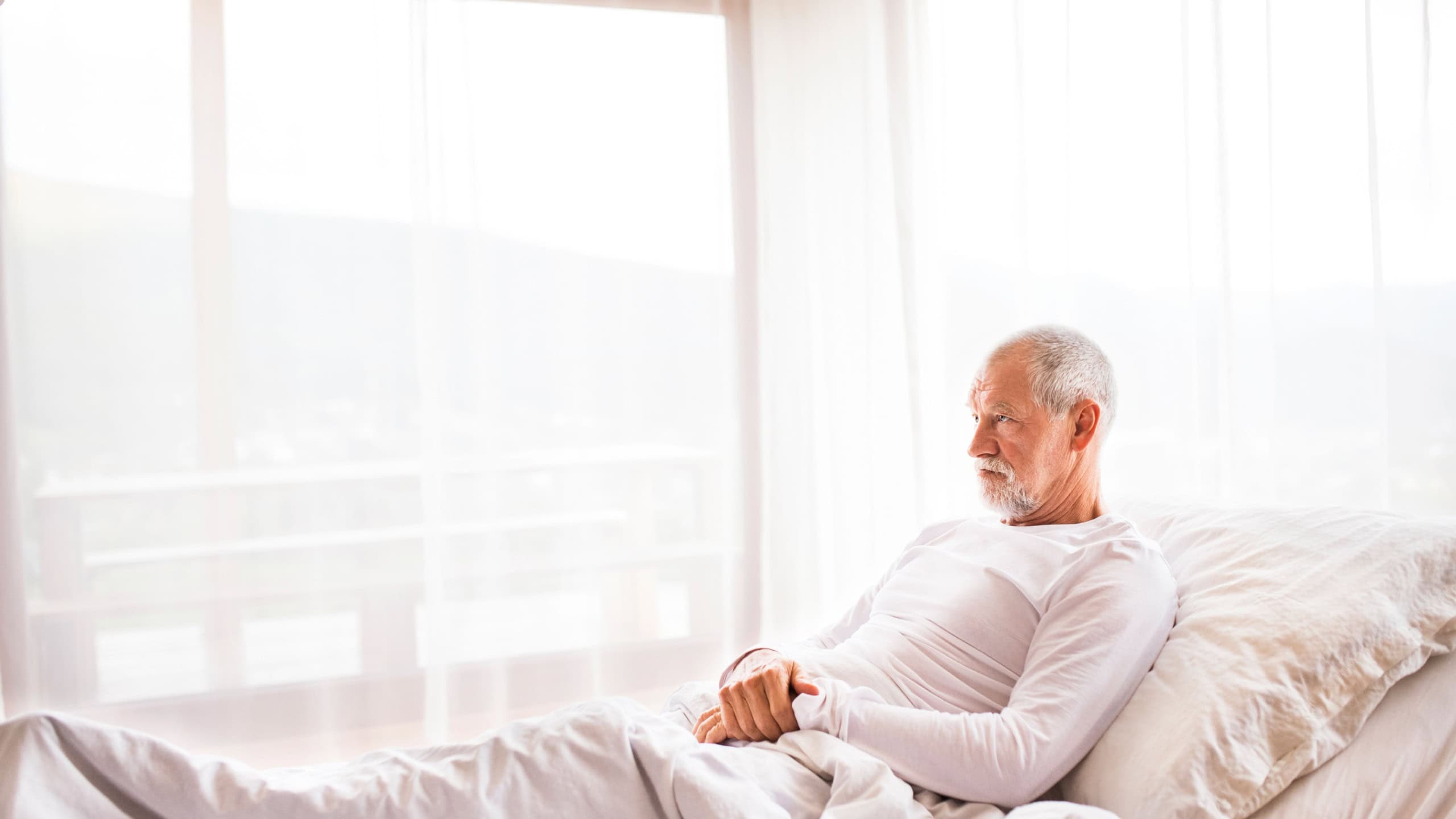 Senior man lying in adjustable bed at home.