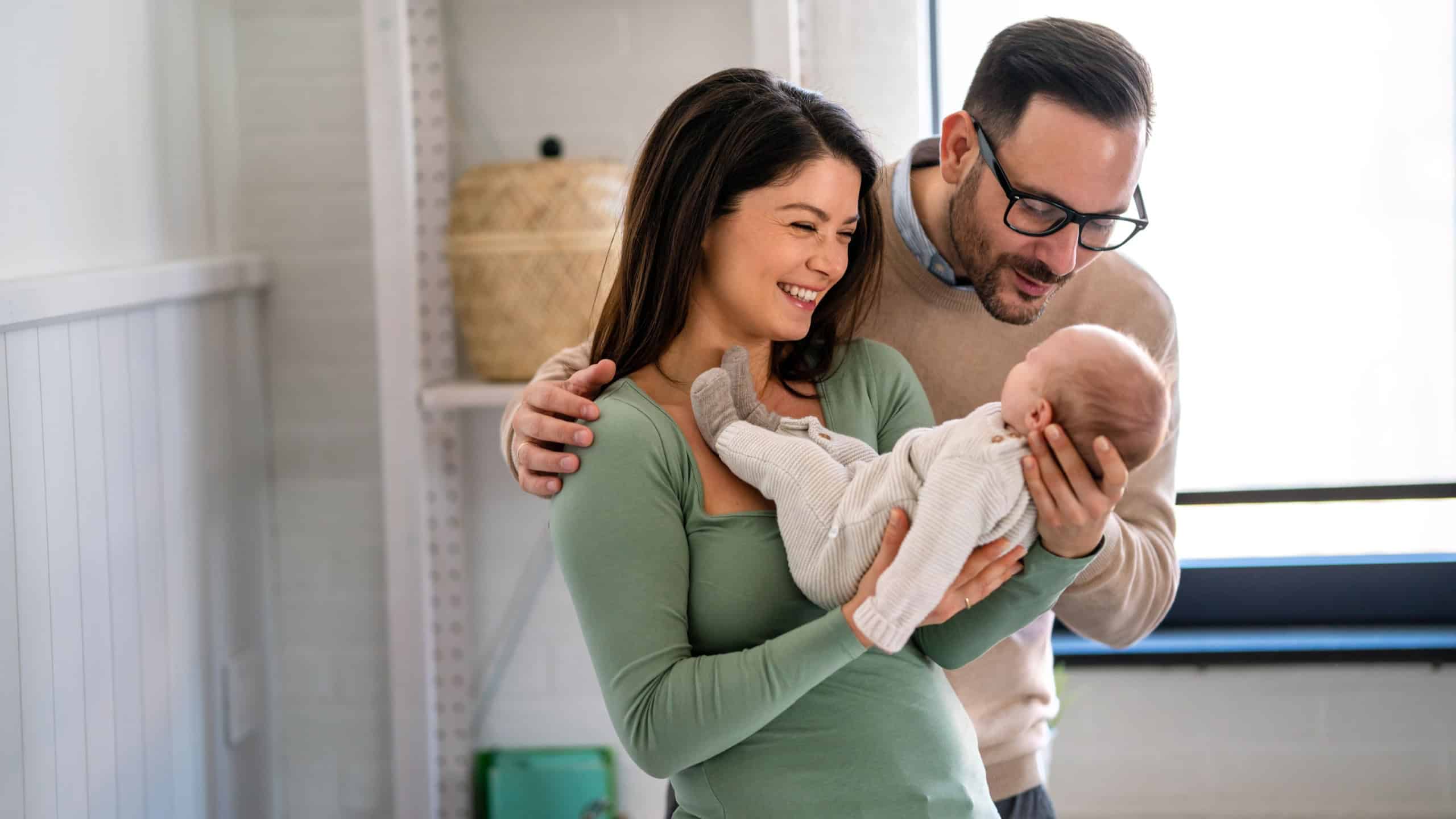 Family, adoption, baby, parenthood and people concept. Happy mother father with newborn baby at home