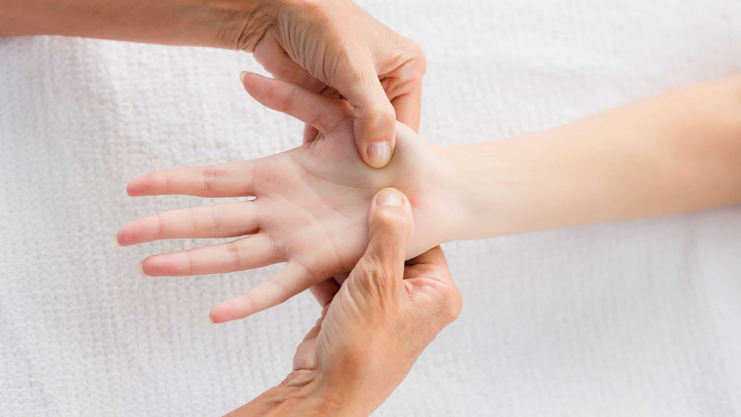 Cropped image of masseur massaging woman hand at spa