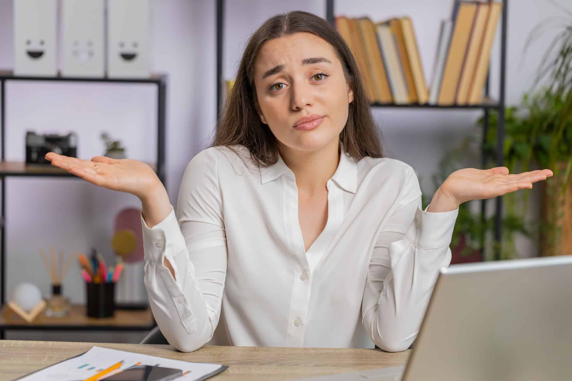 I dont know what to say. Confused business woman works on laptop at office workplace. Freelancer feeling embarrassed about ambiguous question, having doubts, no answer idea, being clueless, uncertain