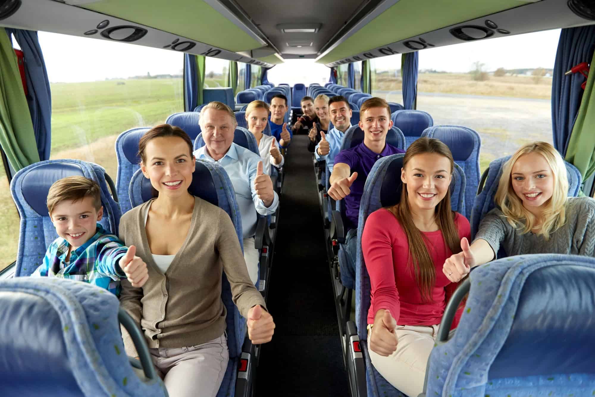 transport, tourism and travel concept - group of happy passengers travelling by bus and showing thumbs up