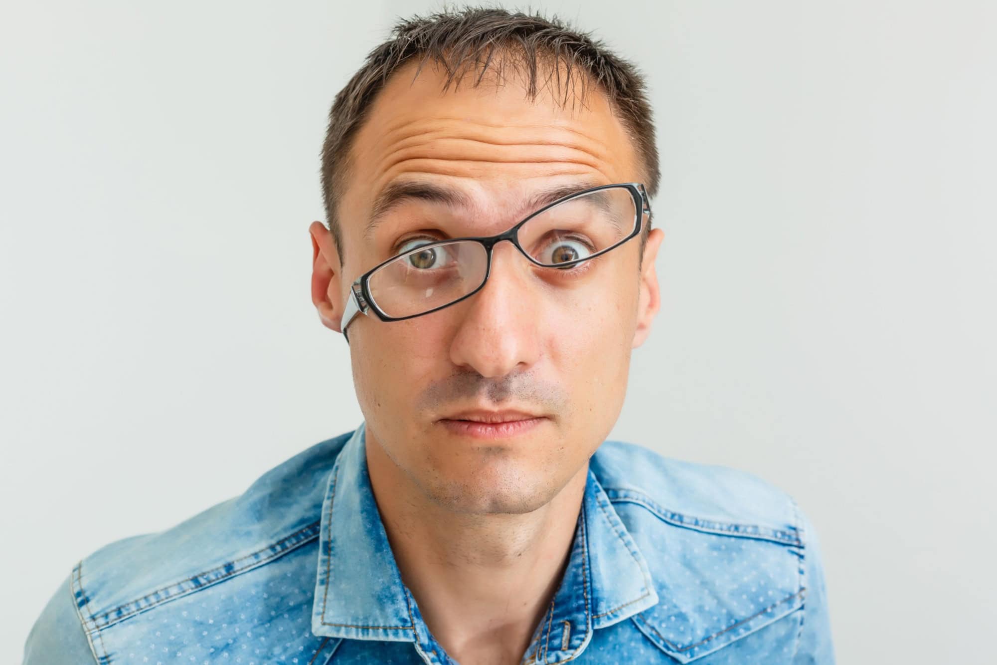 Closeup portrait of frustrated, mad angry nerdy young man with big glasses, screaming fists raised, isolated on white background. Negative emotions facial expressions feelings, body language