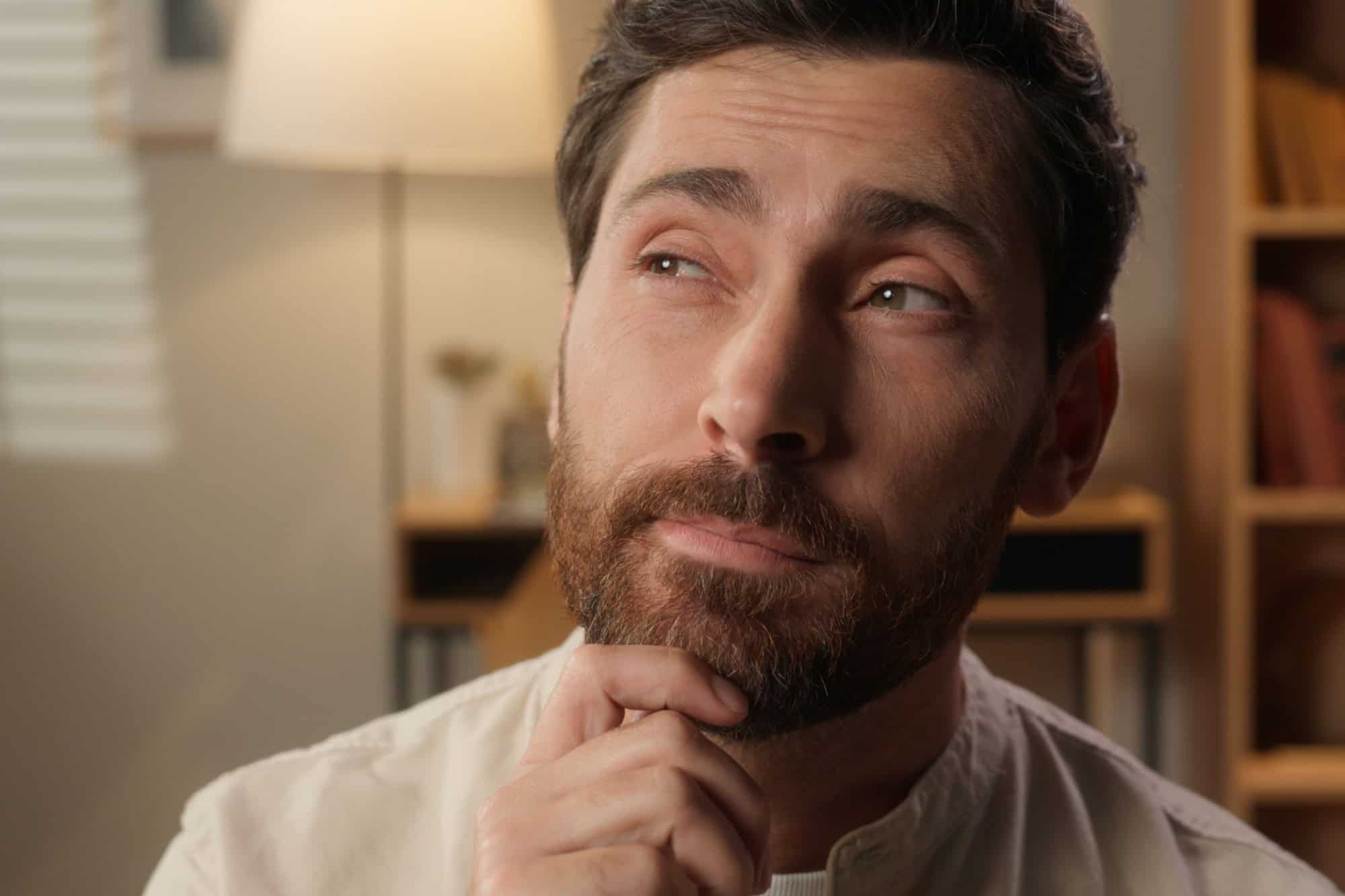 Close up thinking businessman adult man Caucasian male homeowner tenant think dream hold hand on chin thoughtful question plan remember smiling guy at home apartment pondering ideas domestic weekend