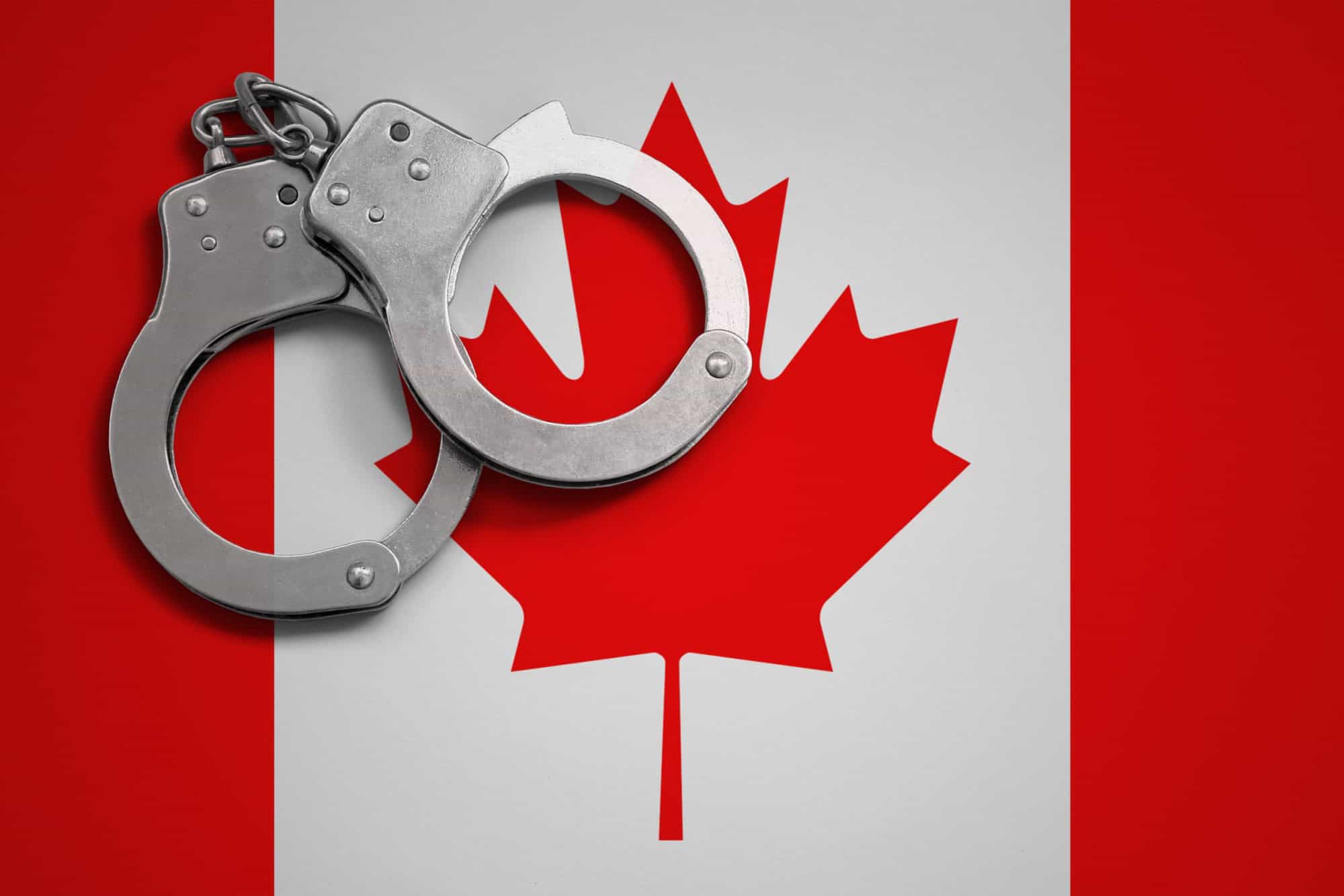 Canada flag and police handcuffs. The concept of crime and offenses in the country