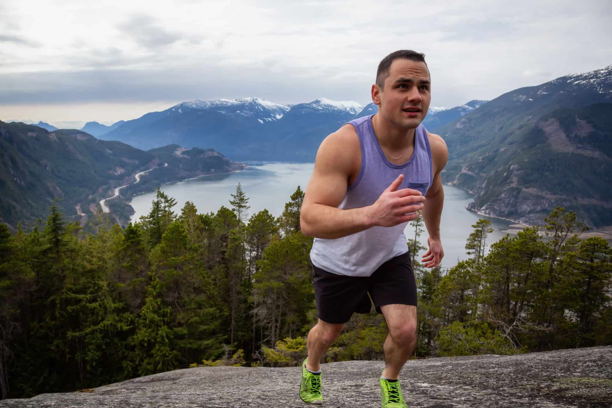 Fit and Muscular Young Man is Running up the Mountain during a cloudy day. Taken on Chief Mountain in Squamish, North of Vancouver, BC, Canada.