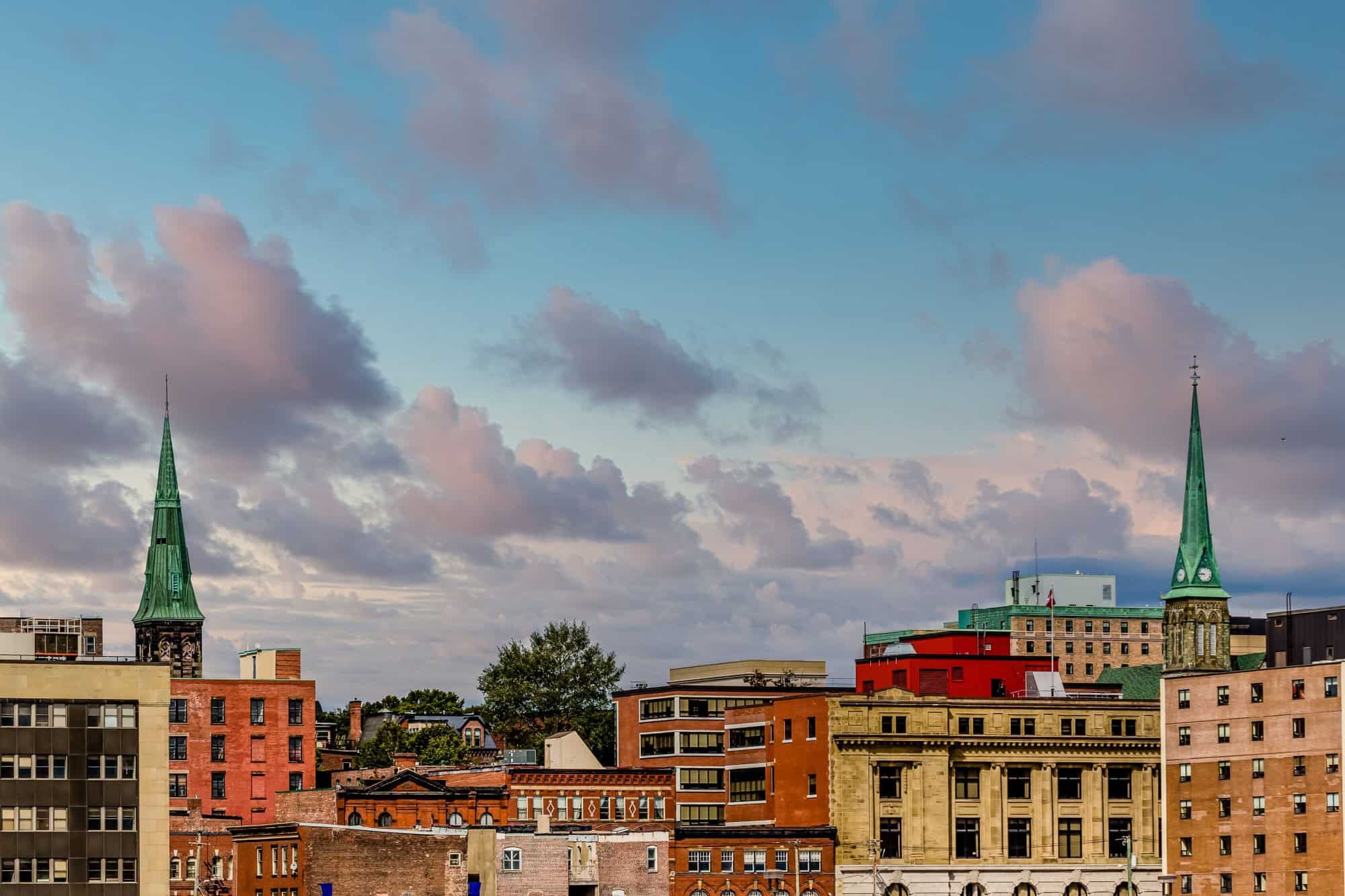 Two green church steeples above old brick buildings in Saint John, New Brunswick, Canada
