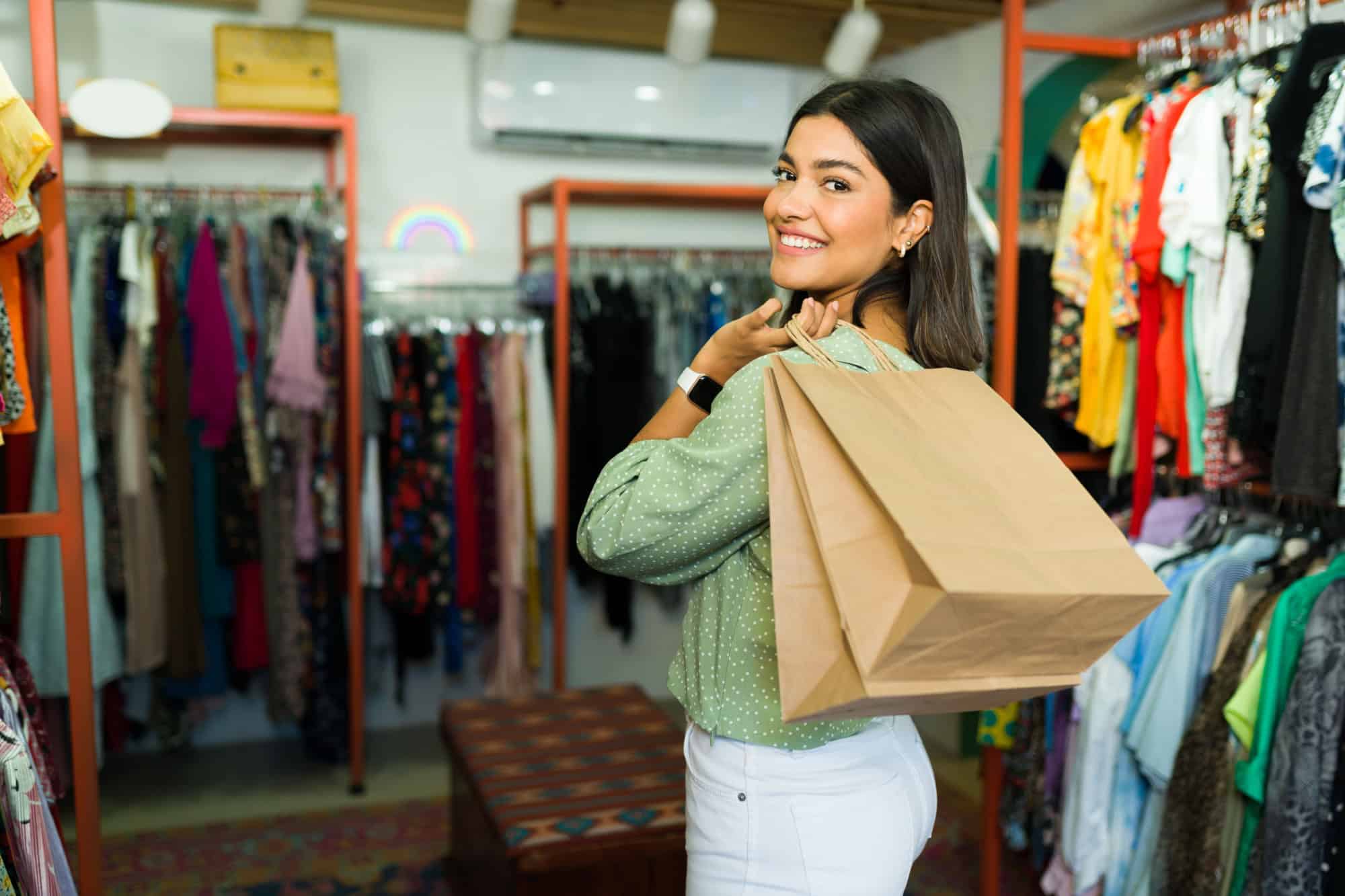 Beautiful woman enjoying going shopping for new outfits. Young woman leaving the store with shopping bags