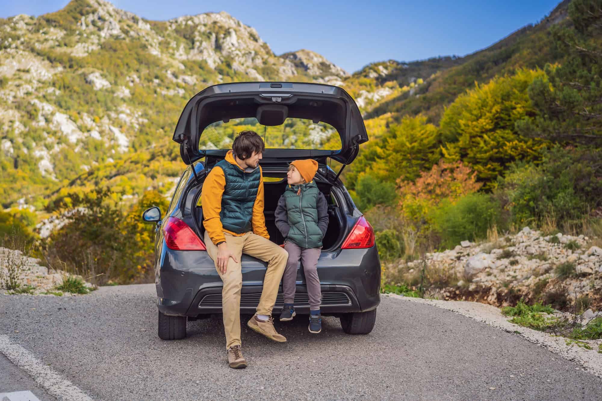 Dad and son are resting on the side of the road on a road trip. Road trip with children concept