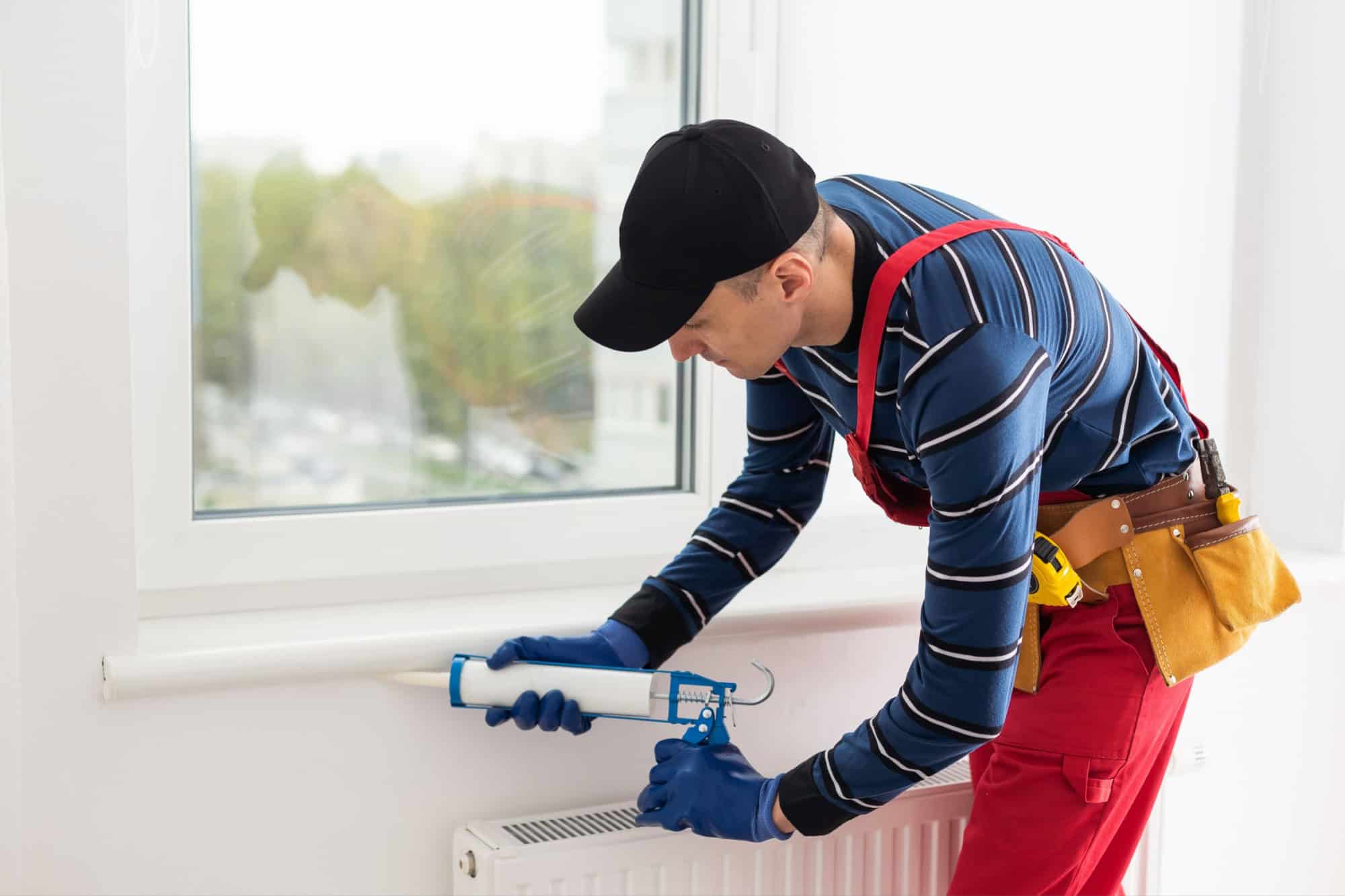 Construction worker sealing window with caulk, closeup