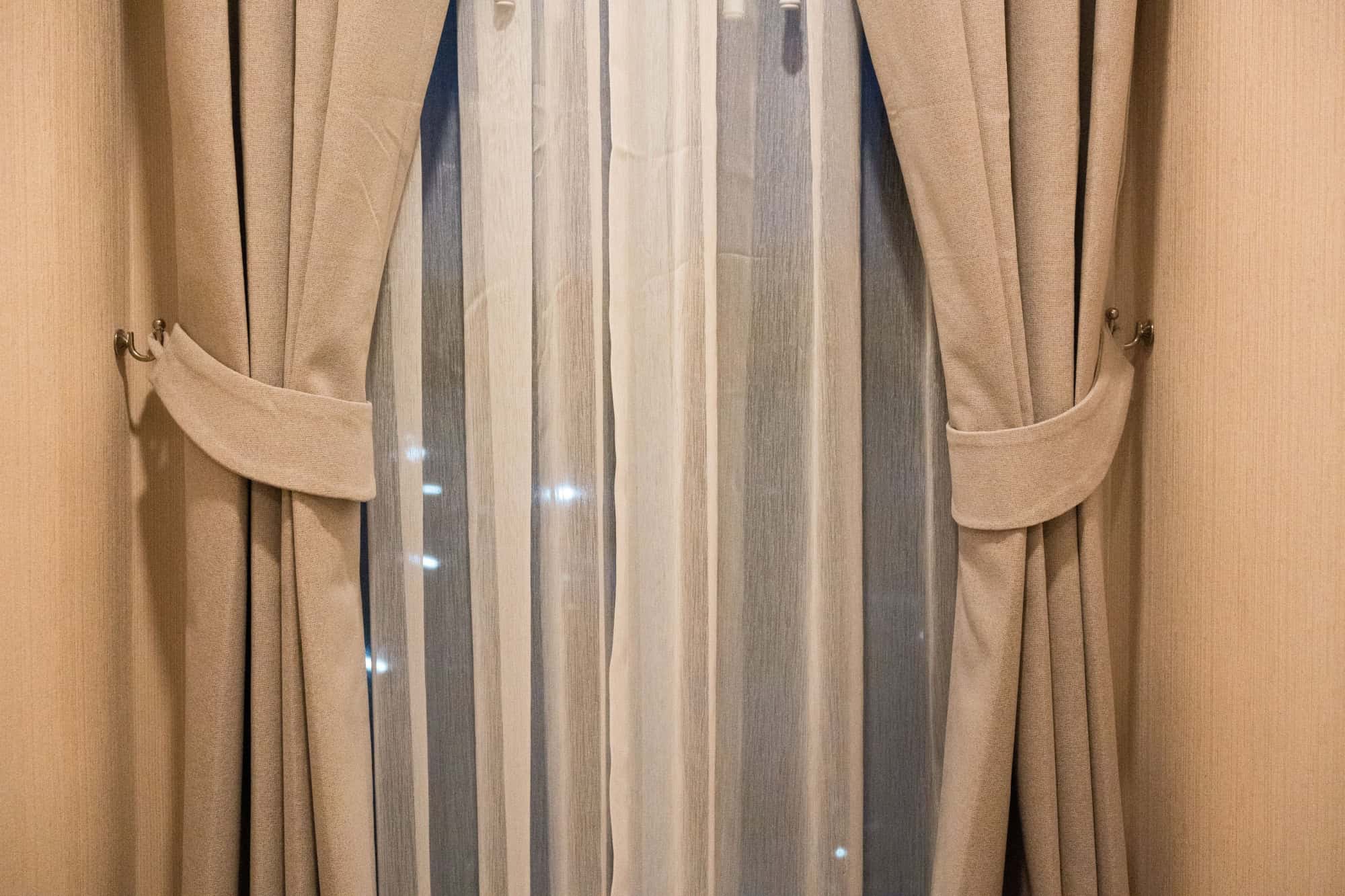 Night brown curtains on the windows in the interior. White transparent day curtains and brown blackout curtains.