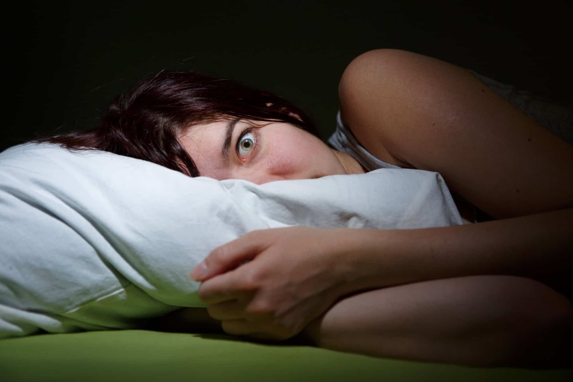 Young woman in bed eyes opened suffering insomnia. Nightmare issues