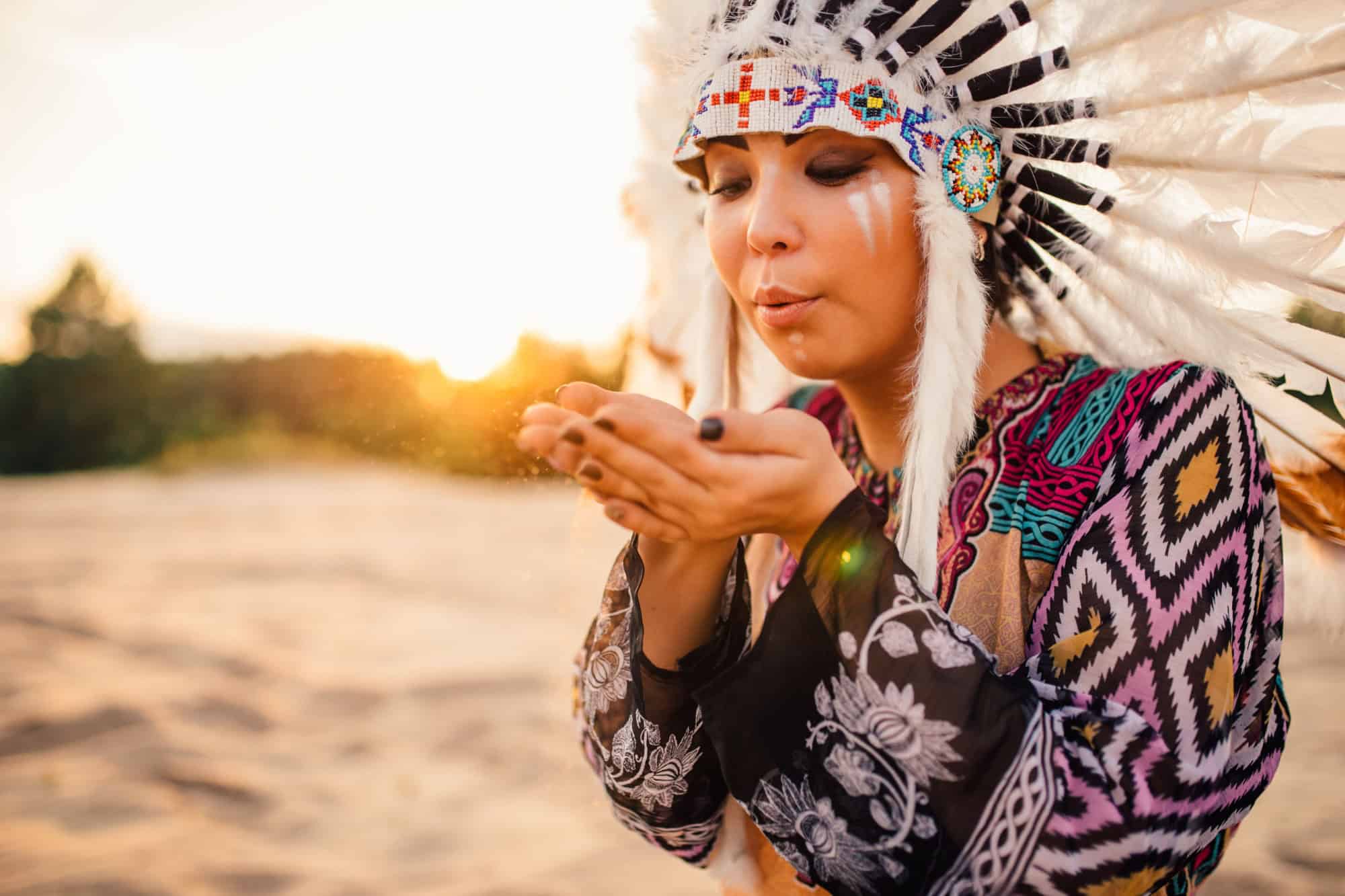 Female American Indian play with sand on sunset