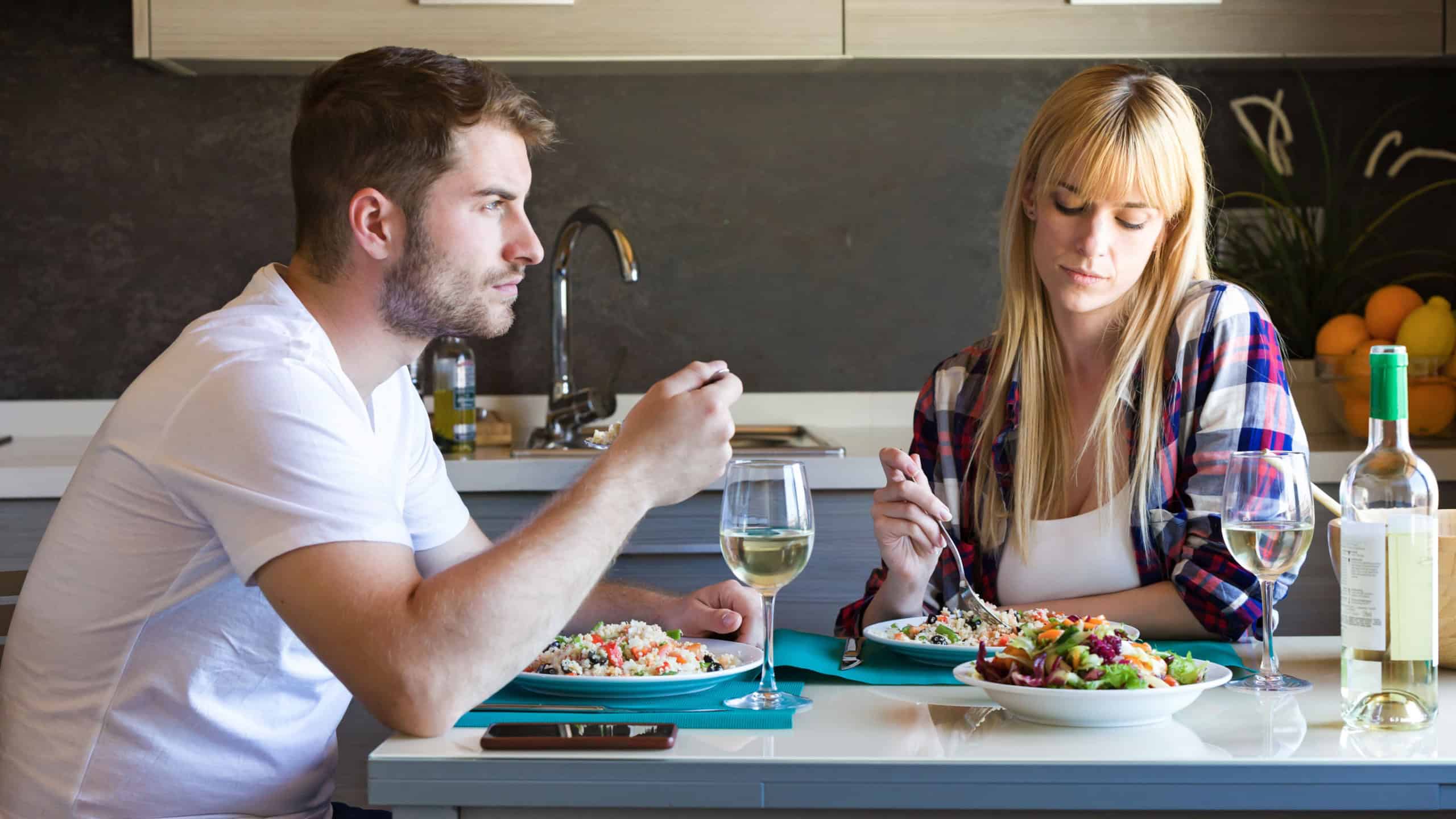 Shot of serious and unhappy young couple eating quinoa salad in the kitchen at home.