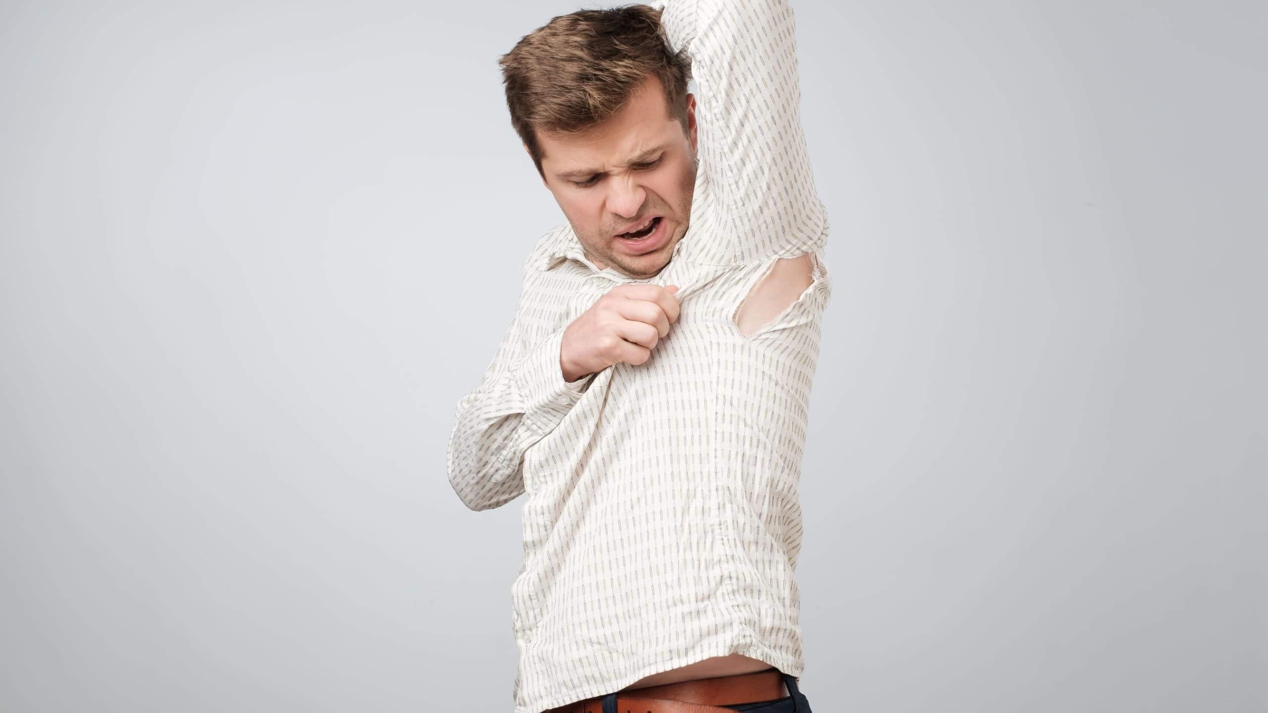 A young handsome man accidentally tore his shirt on his armpit.