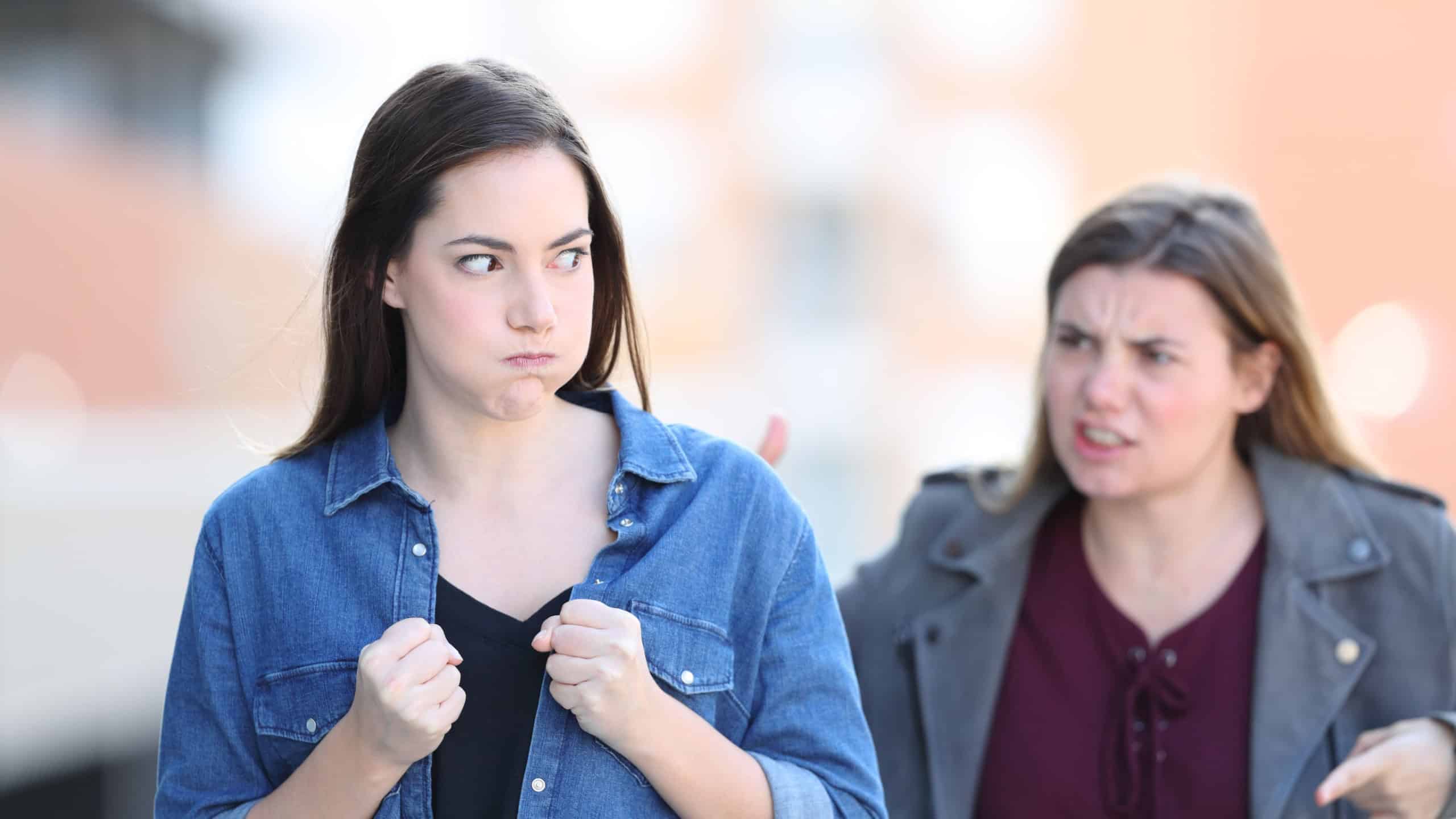 Front view portrait of two angry friends arguing in the street
