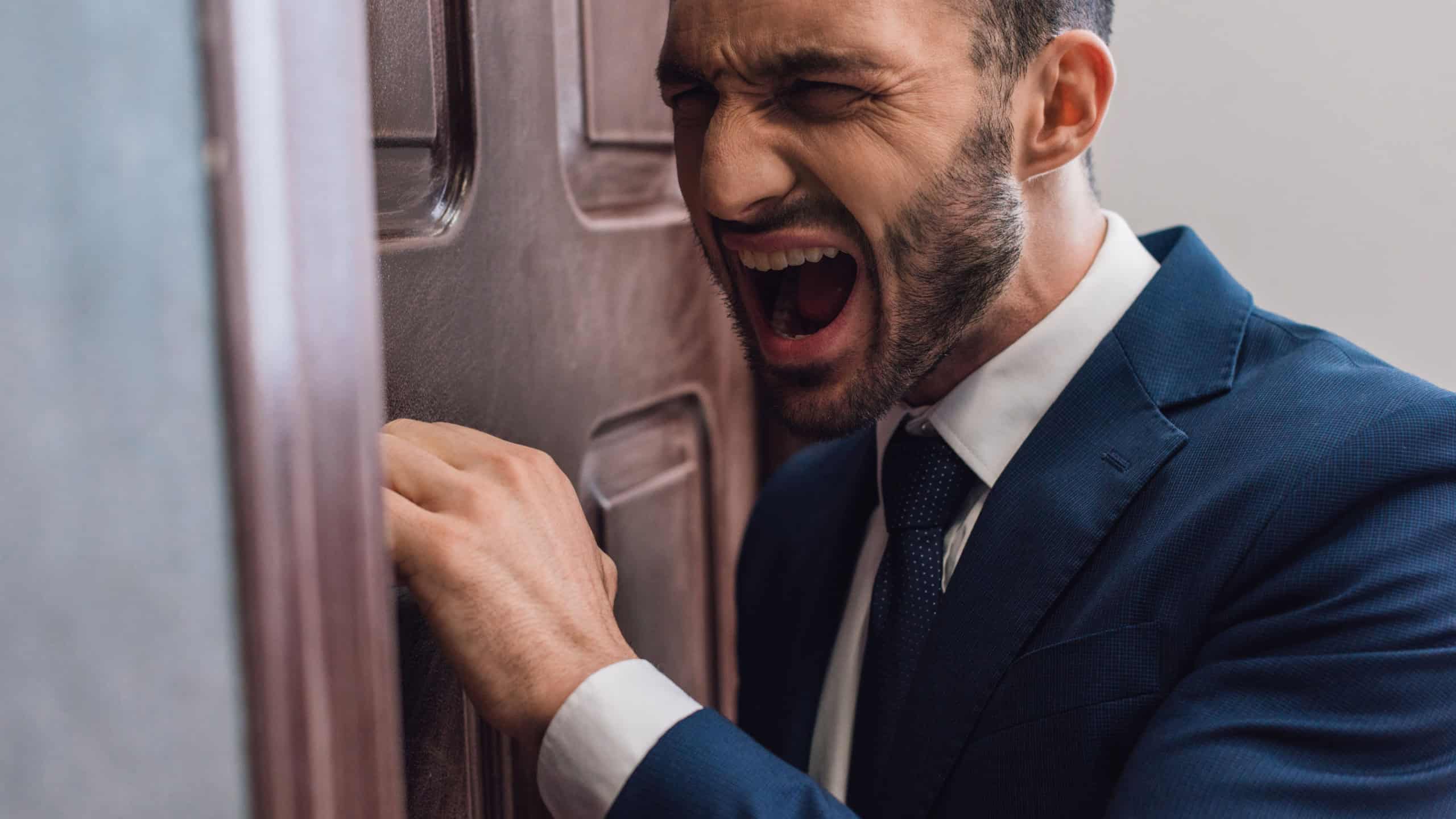 Selective focus of angry person shouting and knocking on door