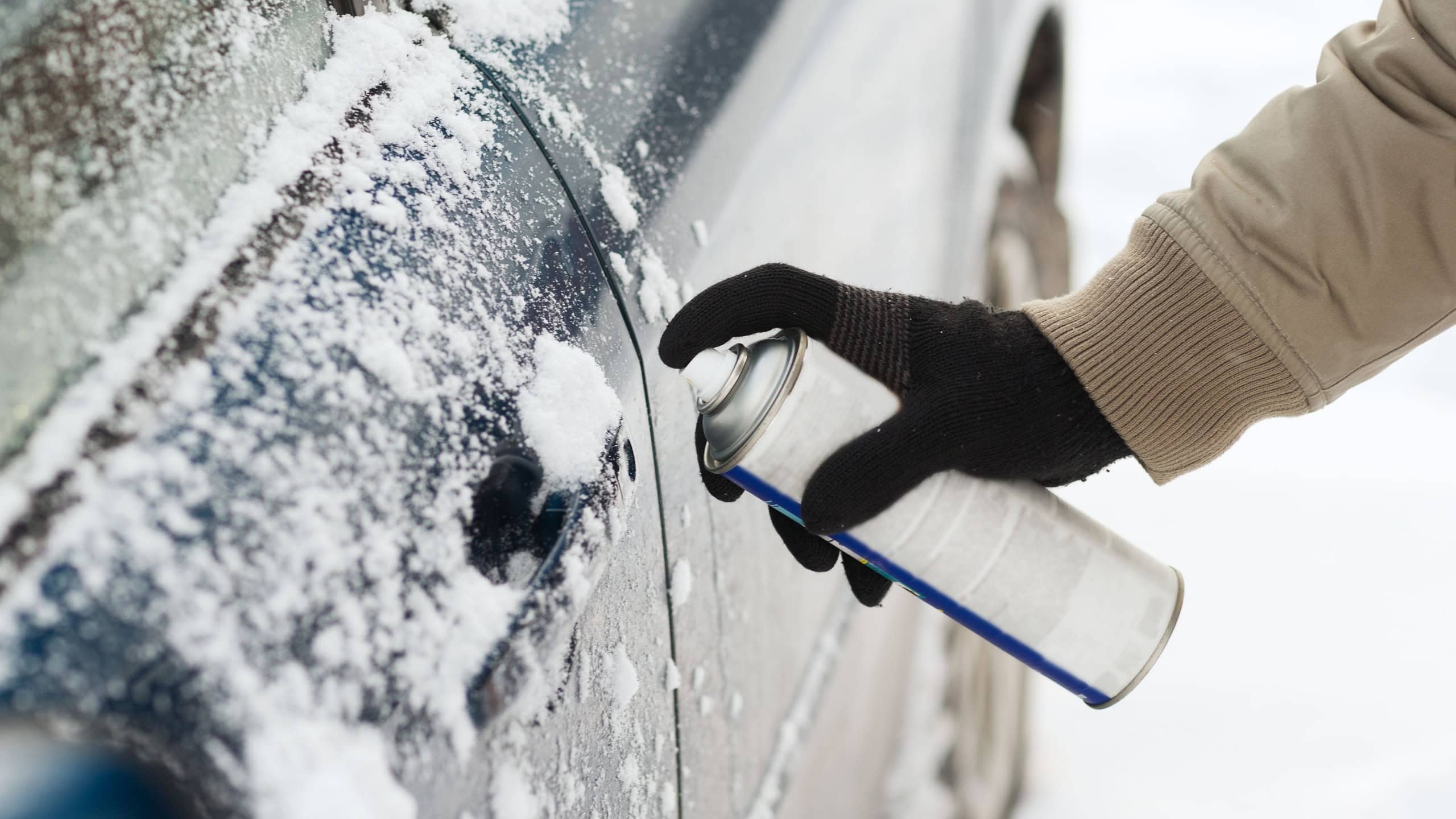 Transportation, winter and vehicle concept - closeup of man hand with lock door de-icer