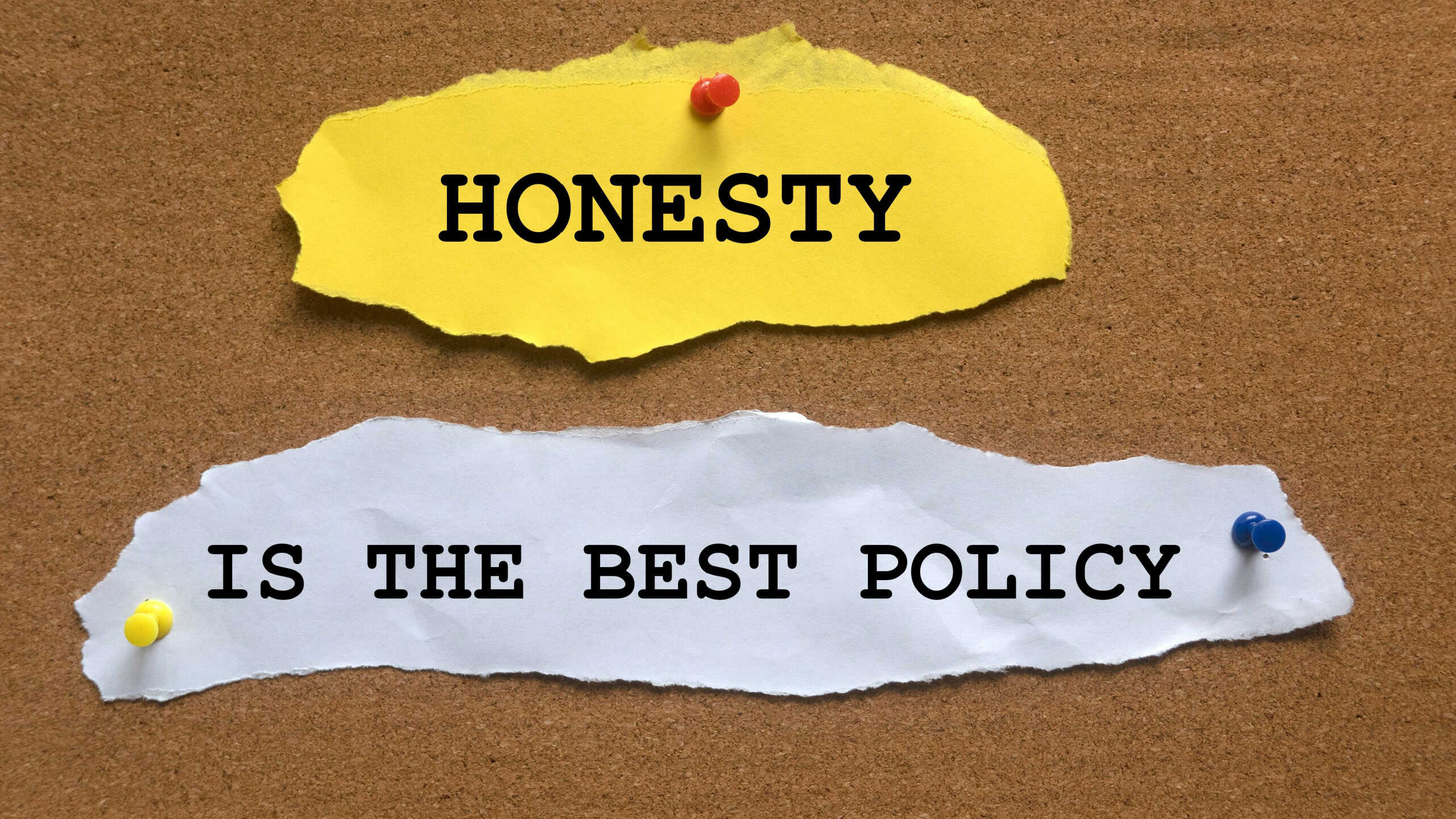 A torn paper with quotes Honesty Is The Best Policy on a cork board.