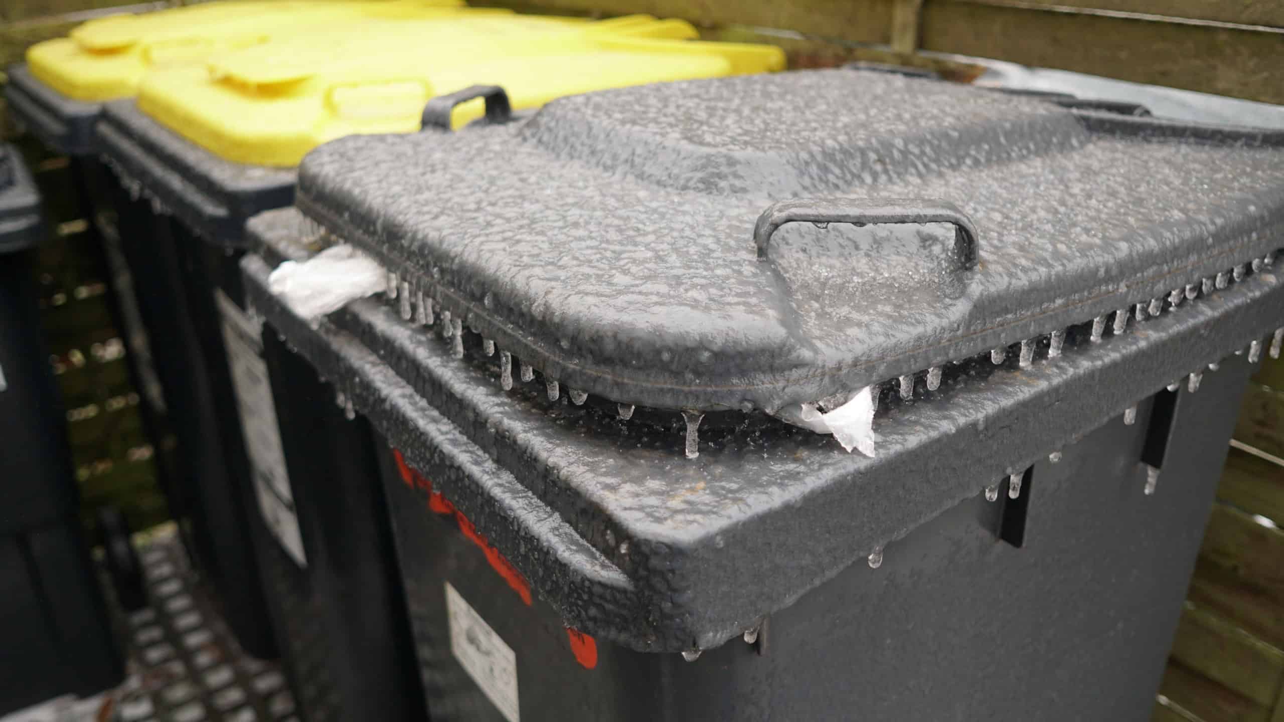 A closeup shot of trash bins frozen in winter