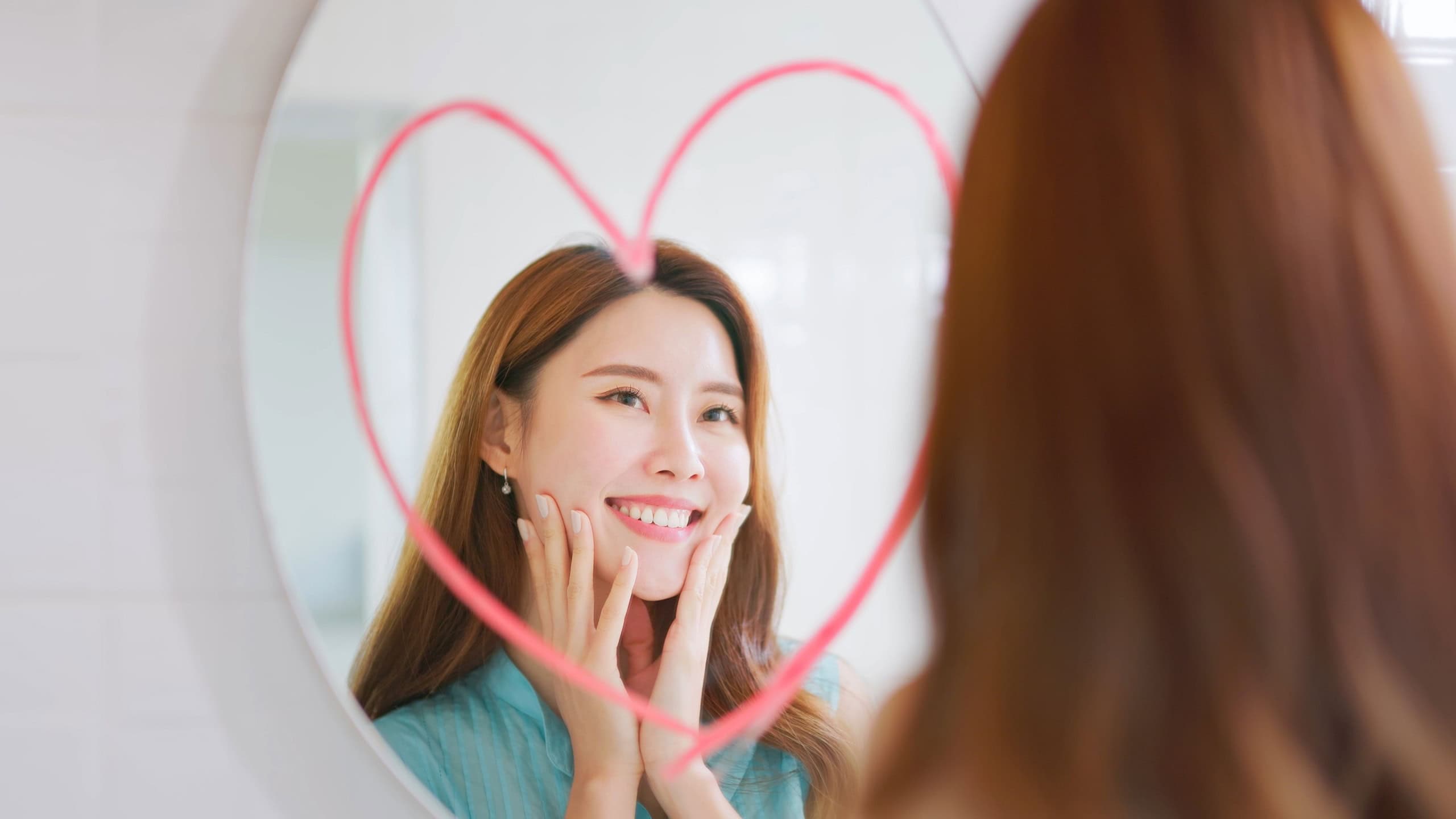 Smiling woman looking in mirror with big red heart shape