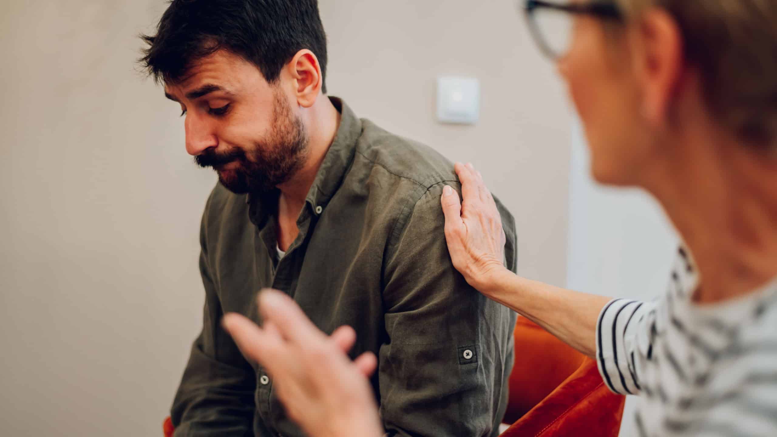 Portrait of a sad caucasian young man sharing his problem with other patients while participating in group therapy session. 