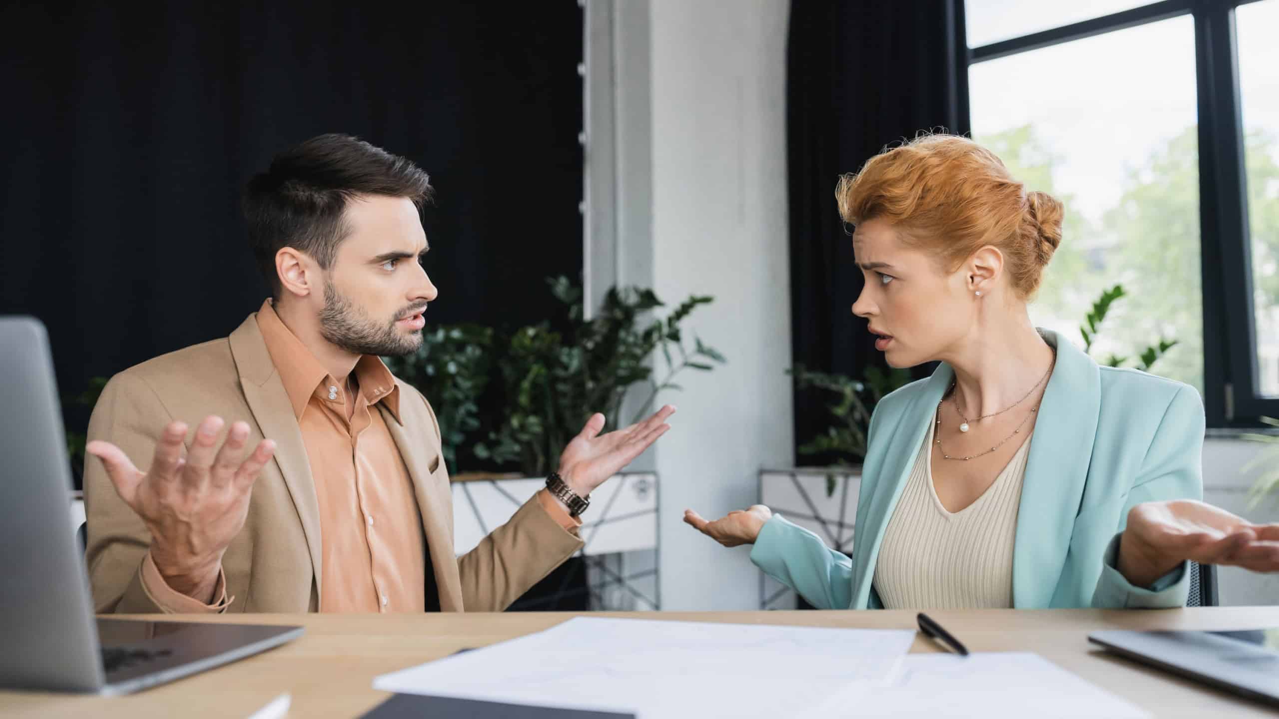 Confused managers showing shrug gesture while talking near documents in office