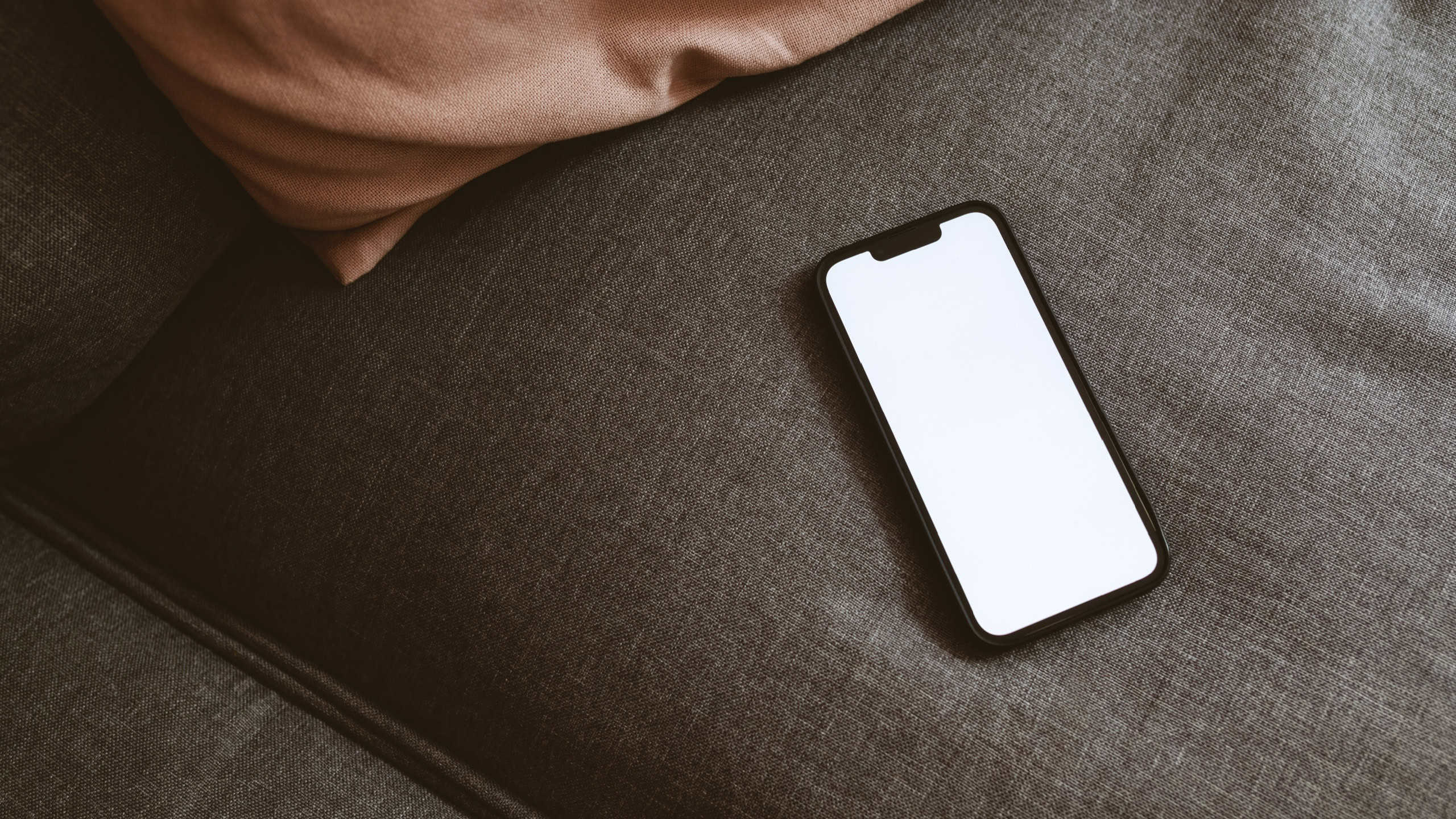 Smart mobile phone device with blank white mockup screen on living room sofa, selective focus