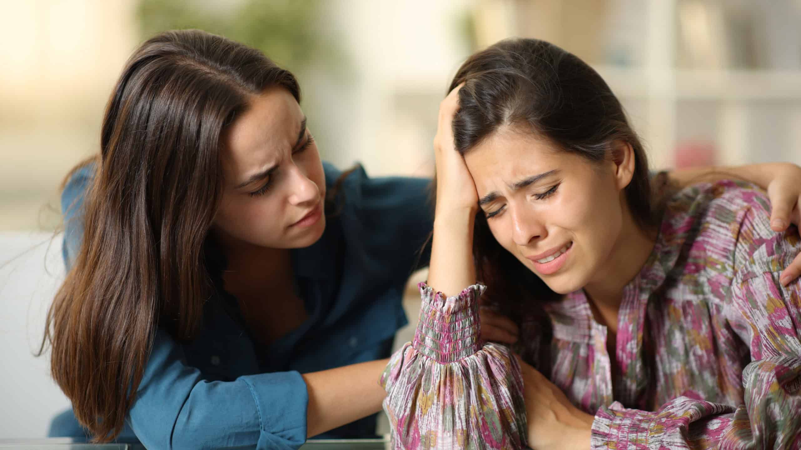Good friend comforting a sad woman at home