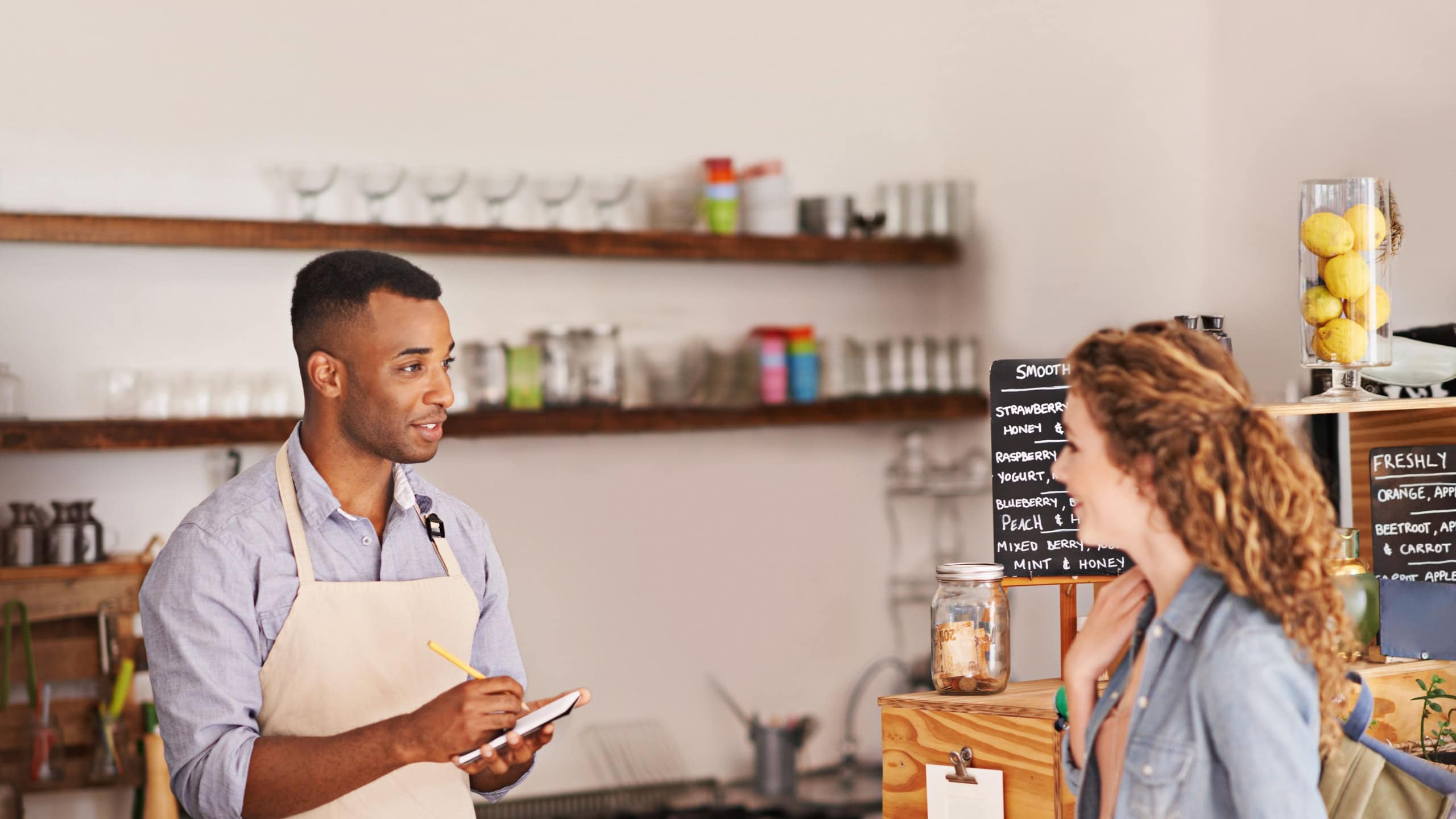 Woman, coffee shop and waiter with writing at counter for shopping, purchase and lunch at cafe. Female person, small business and barista with notepad for discussion, order and customer service