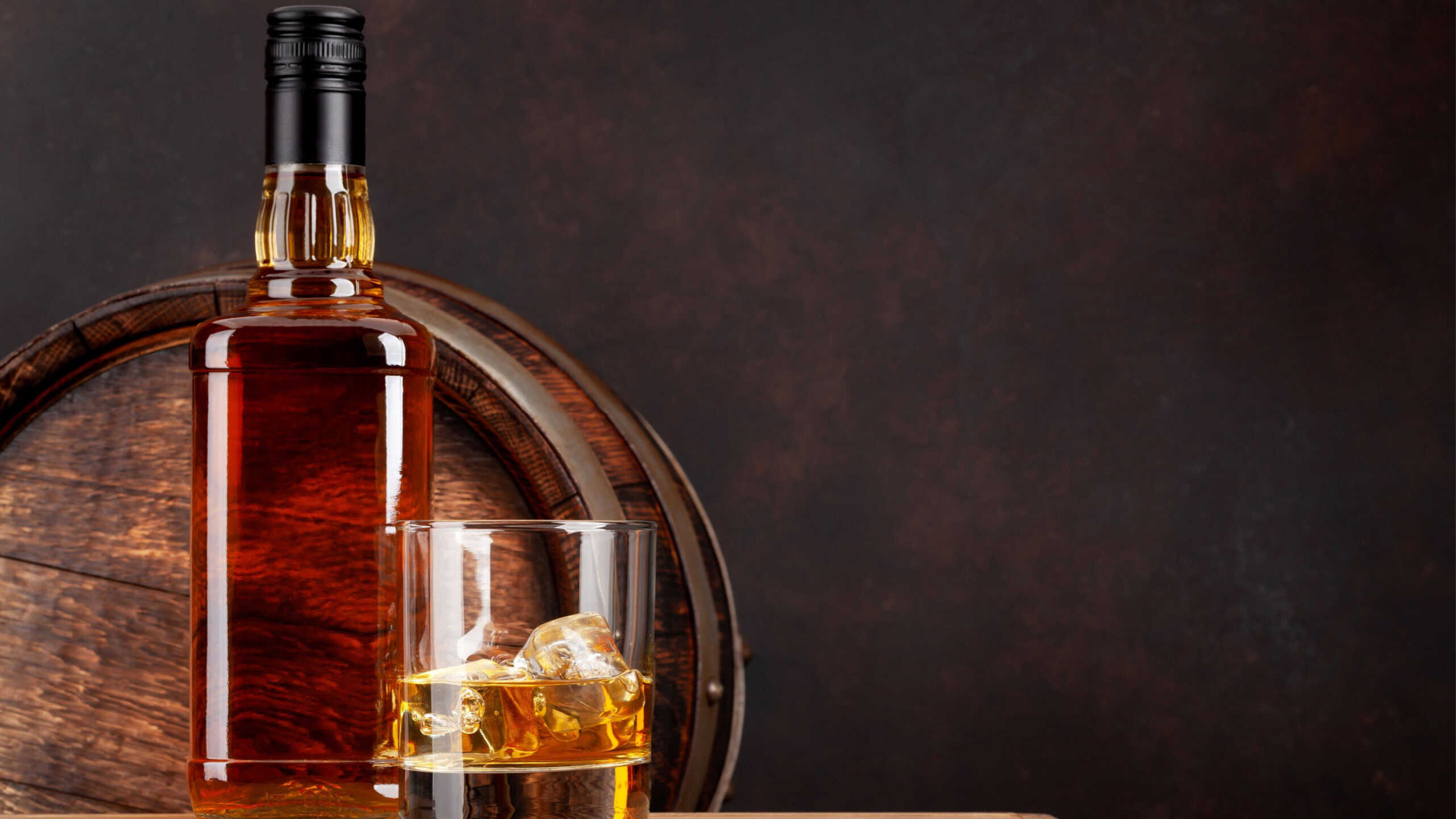 Scotch whiskey bottle, glass and old wooden barrel.