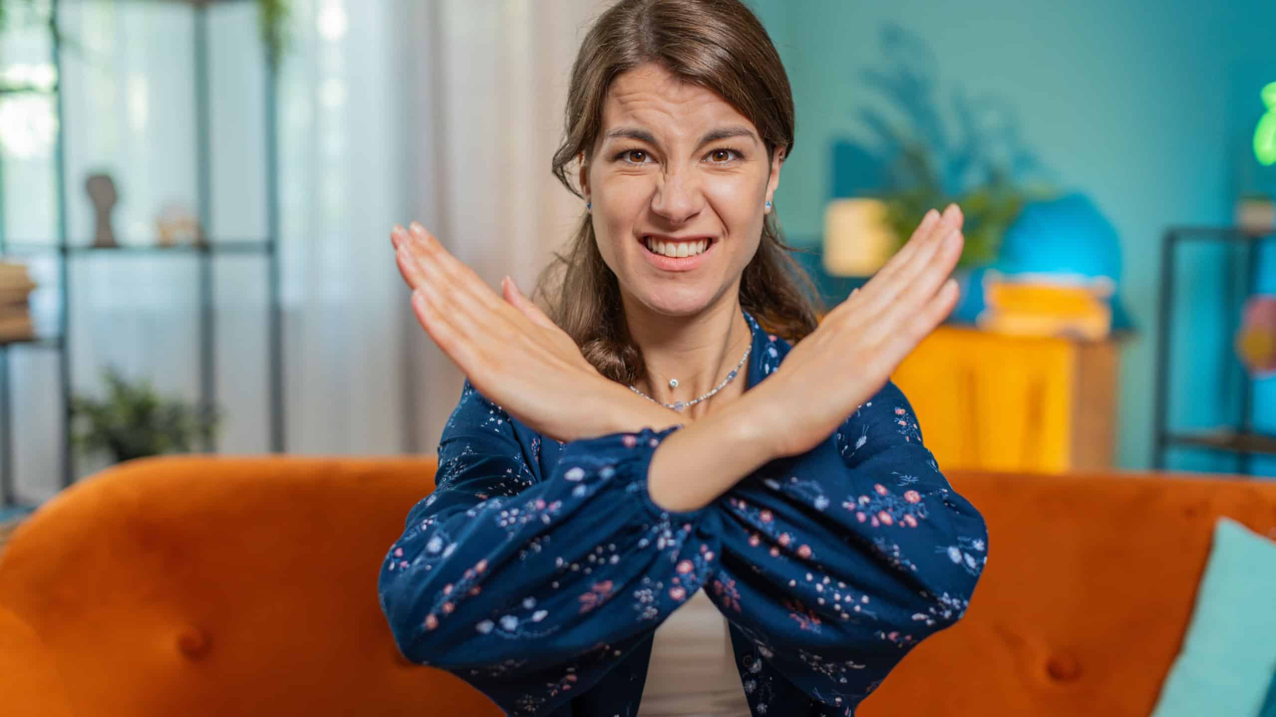Stop gesture. Angry Caucasian woman says No hold palm folded crossed hands, warning of finish, prohibited access, declining communication, body language, danger.
