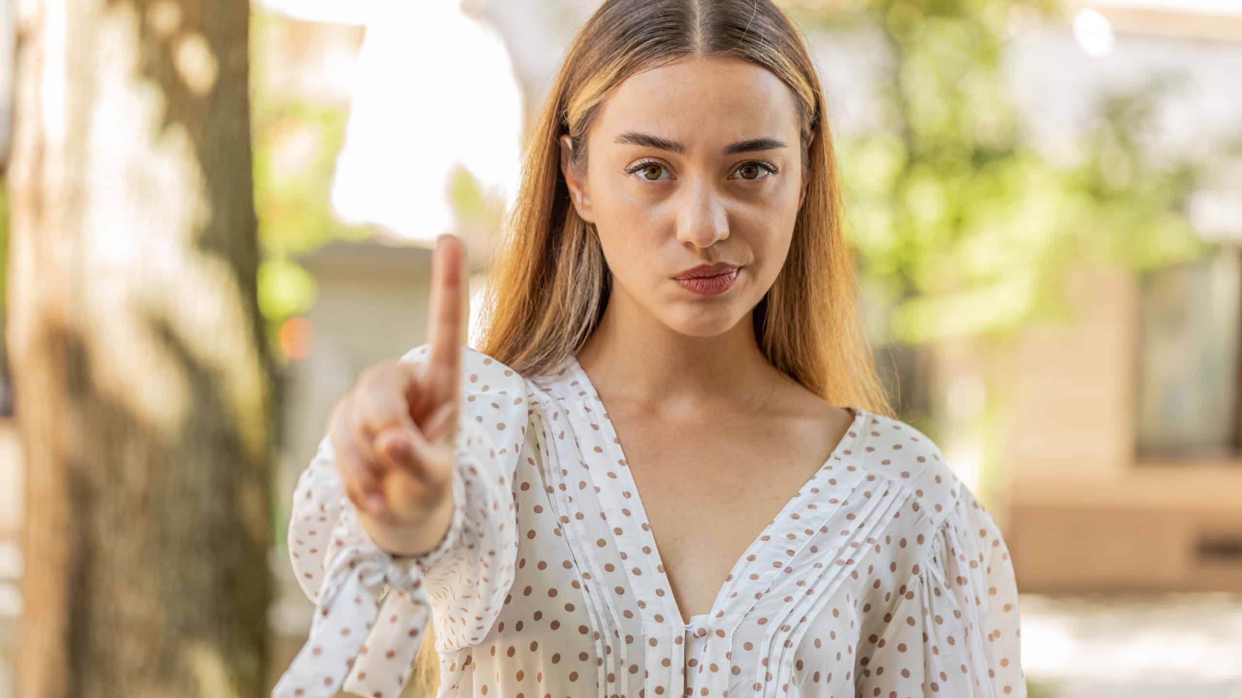 Displeased upset Caucasian woman reacting to unpleasant awful idea, dissatisfied with bad quality, wave hand, shake head No, dismiss idea, dont like proposal. Young adult lady traveler on city street