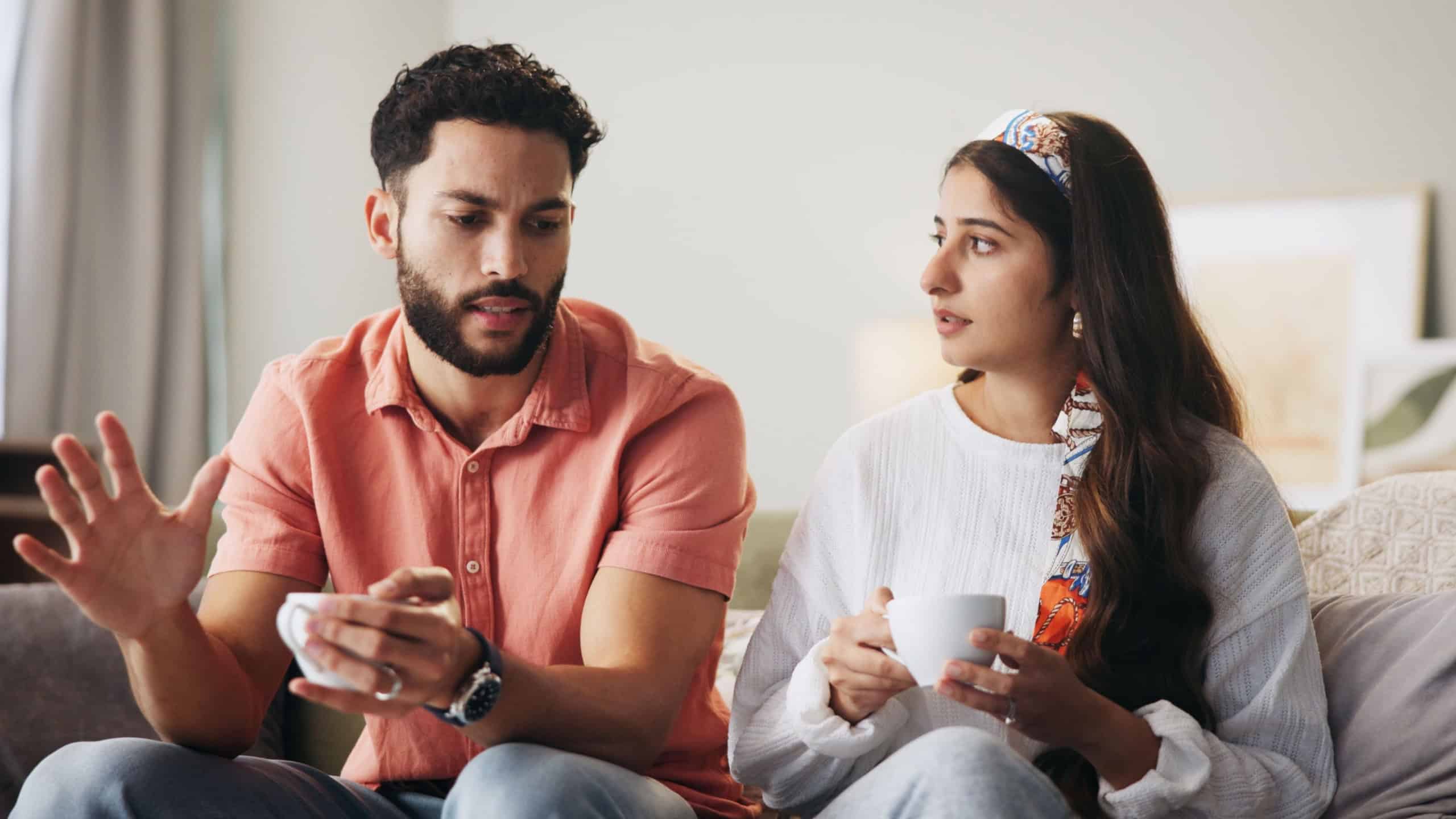 Couple, talk and coffee with fight on sofa for affair, cheating or stress with discussion in lounge. People, man and woman with conversation for dispute, argument and conflict with tea cup in home