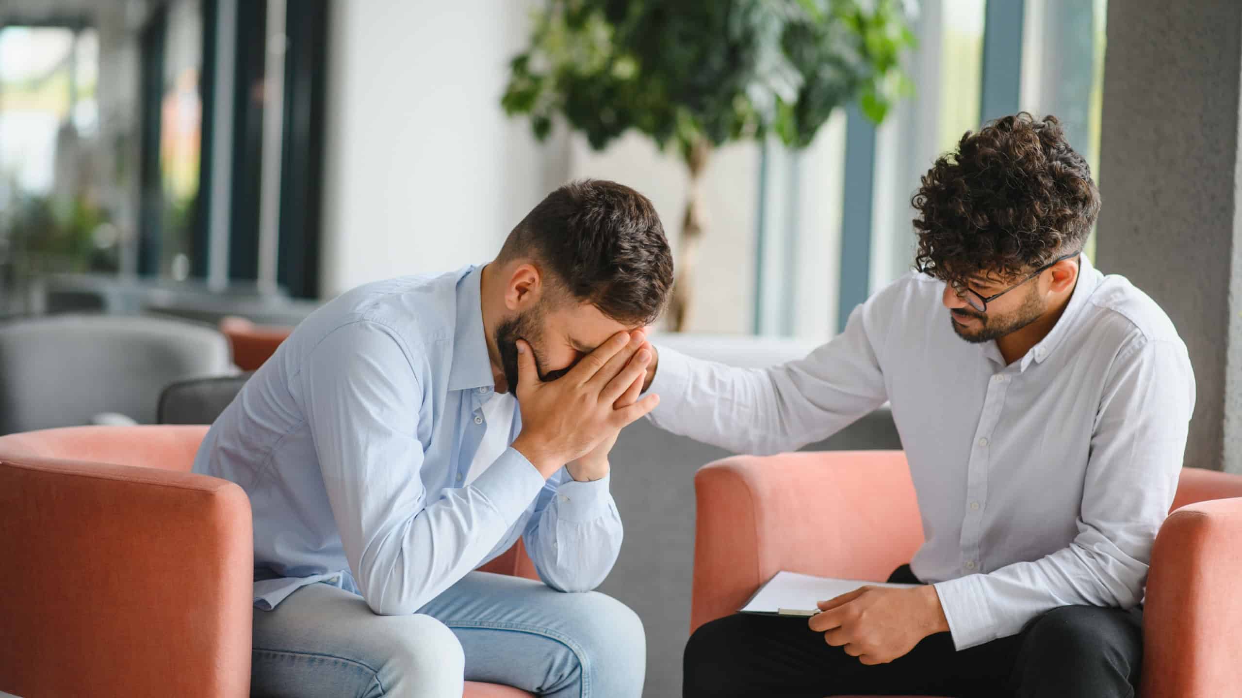 Male patient suffering from psychological problems receiving support from therapist during a session