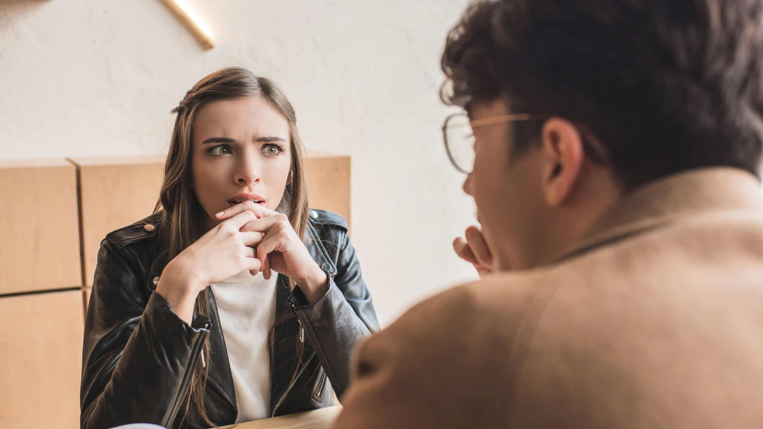 Girl sitting surprised of conversation with a young man in a cafe