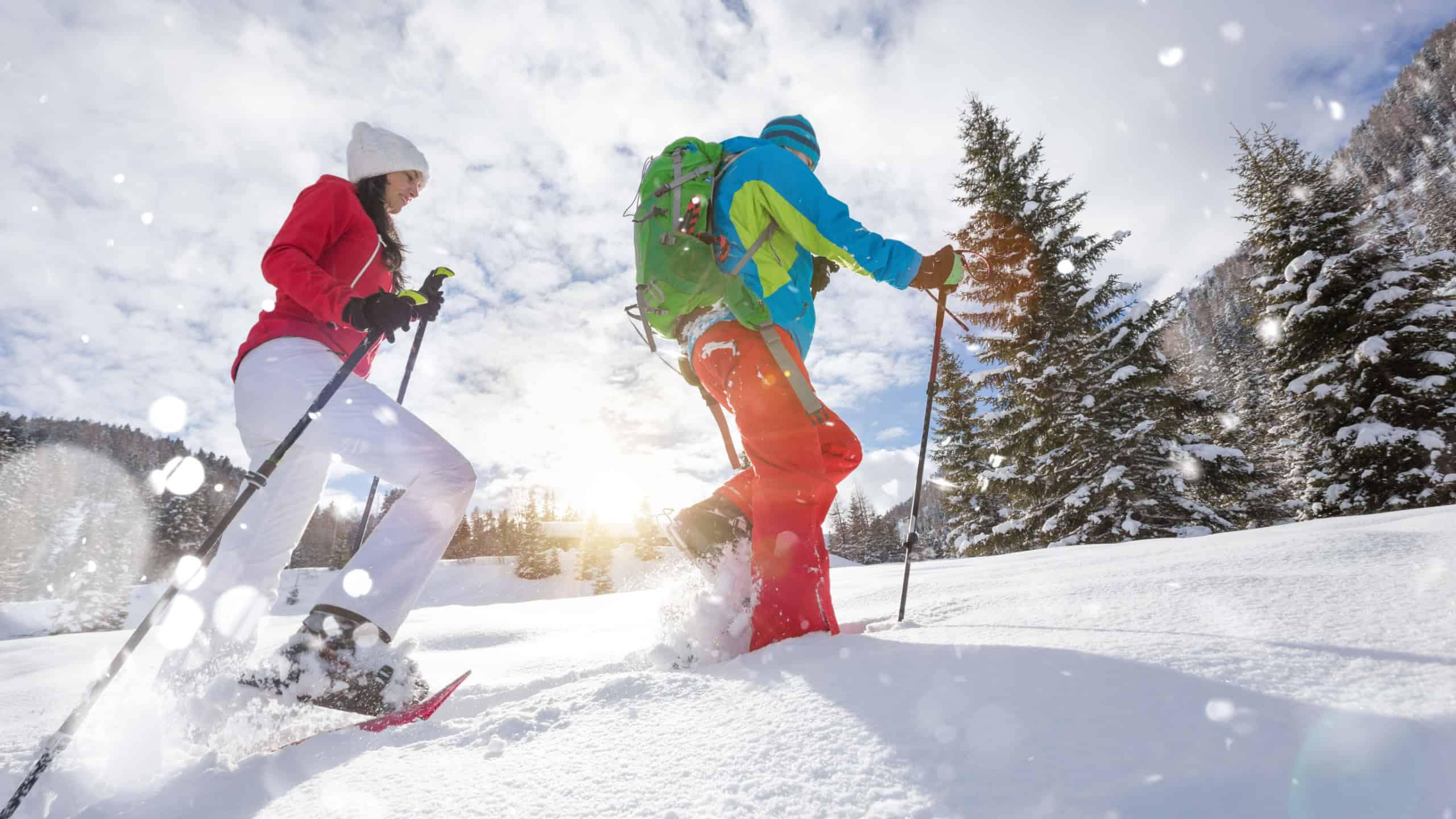 Snowshoe walkers running in powder snow with beautiful sunrise light. Outdoor winter activity and healthy lifestyle