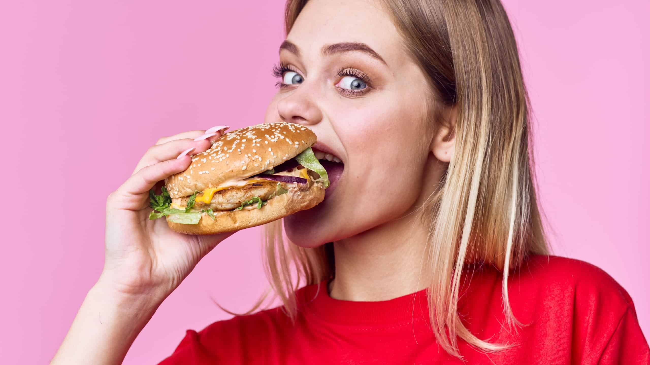 happy woman in red t-shirt eats huge hamburger