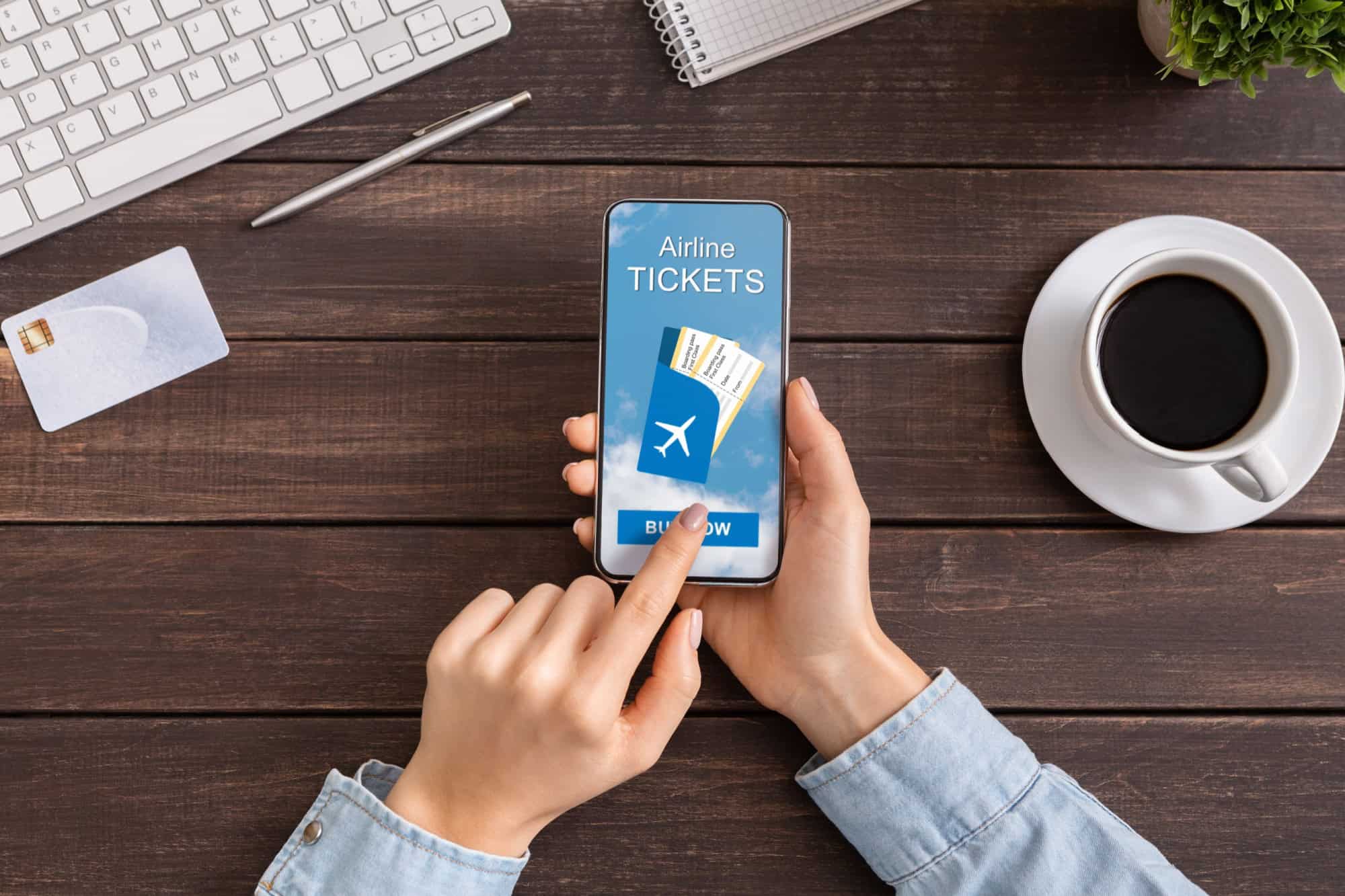 Book your flight. Smartphone with application for buying airline tickets on screen in female hands, top view