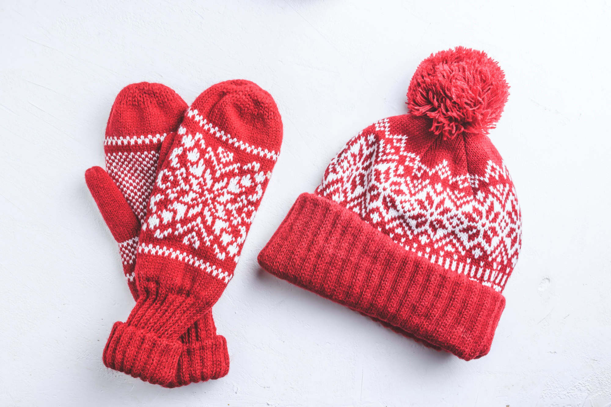 Winter hat and mittens knitted with jackard on white background. Top view. Flst lay. Christmas background