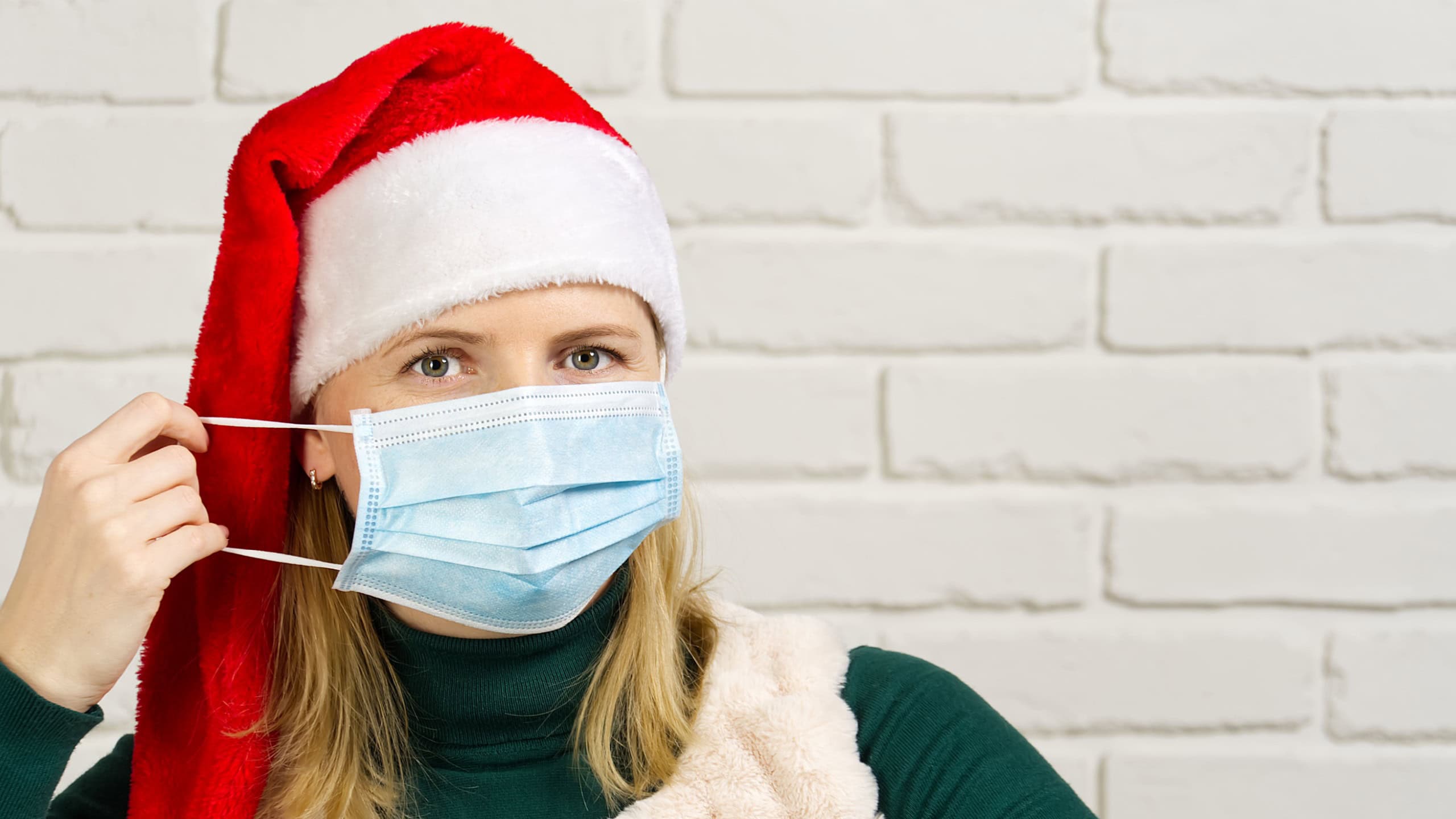woman in red hat wearing medical mask. female wear santa hat. Christmas and New Year in covid concept.
