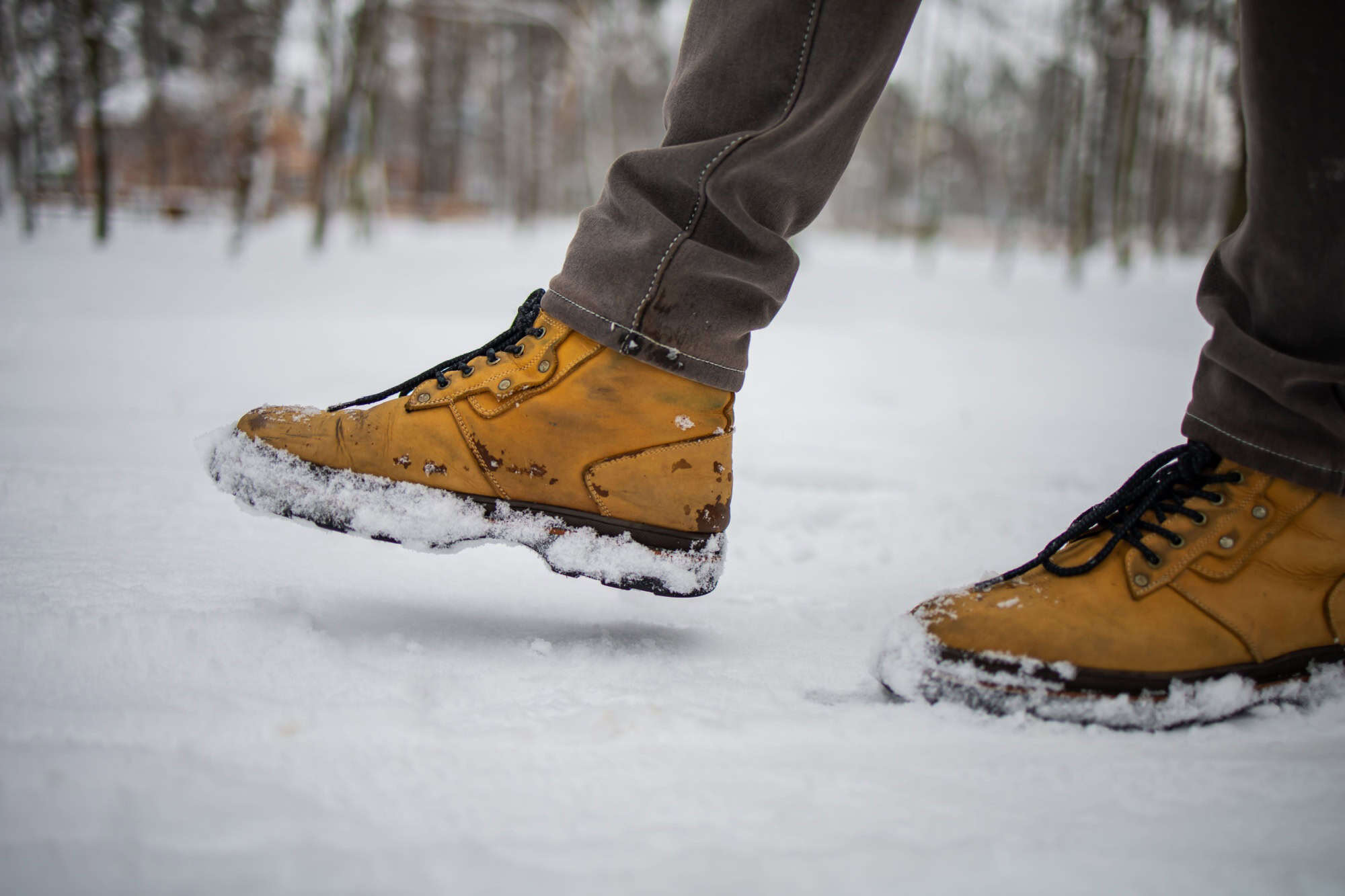 Male Feet In Boots Walking In Winter Snow